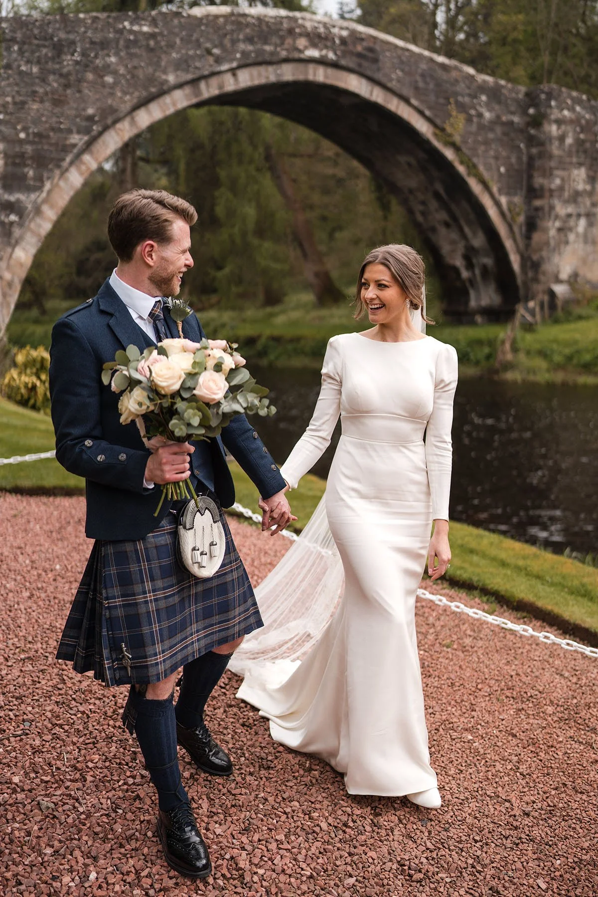 Bride and groom walking hand in hand at Brig o’ Doon in Ayrshire on their wedding day