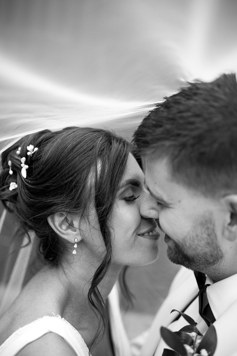 Black and white photo of a bride and groom with their foreheads touching, smiling gently, during their wedding at Engine Works Glasgow