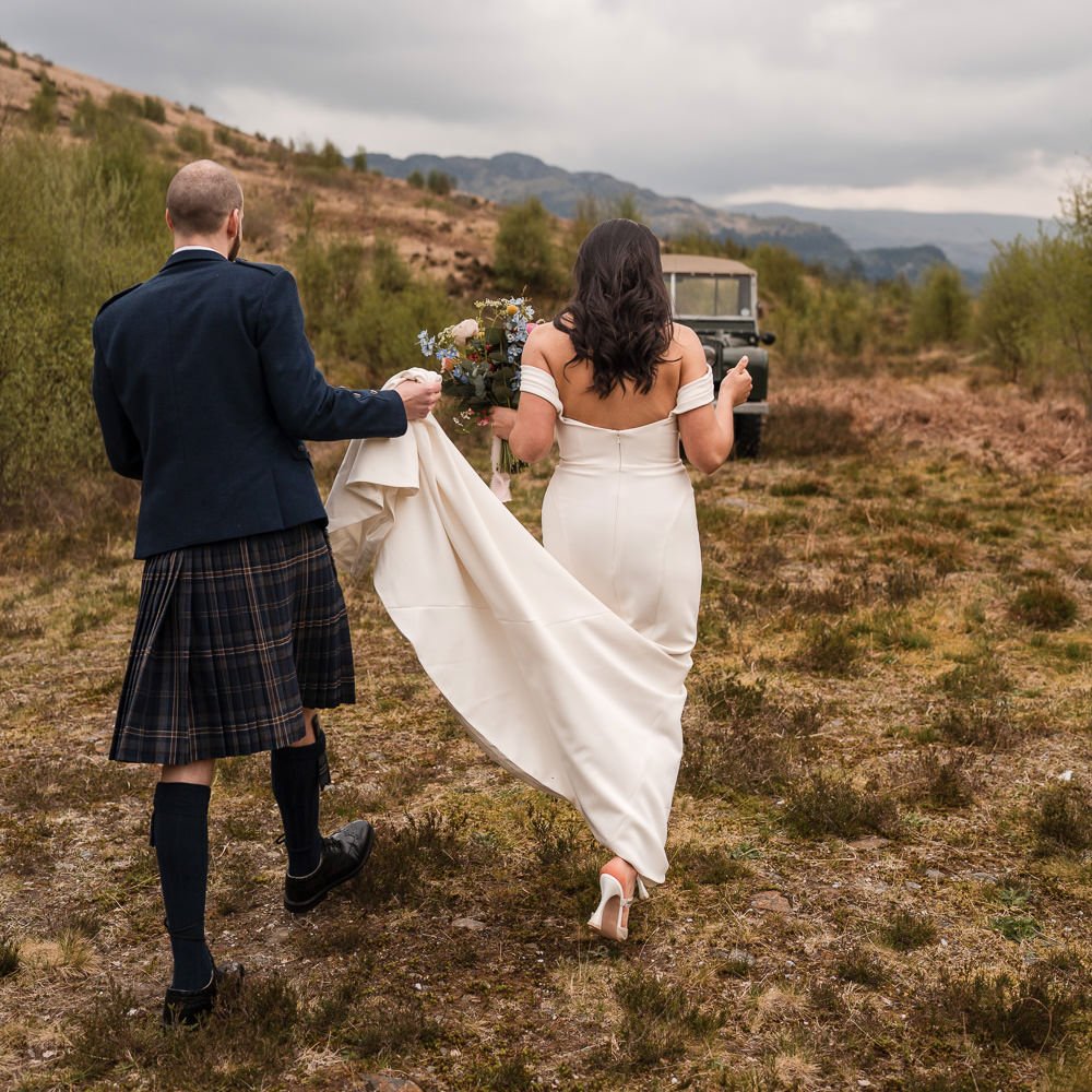 Bride and groom walking together across the Scottish Highlands during their wedding portraits