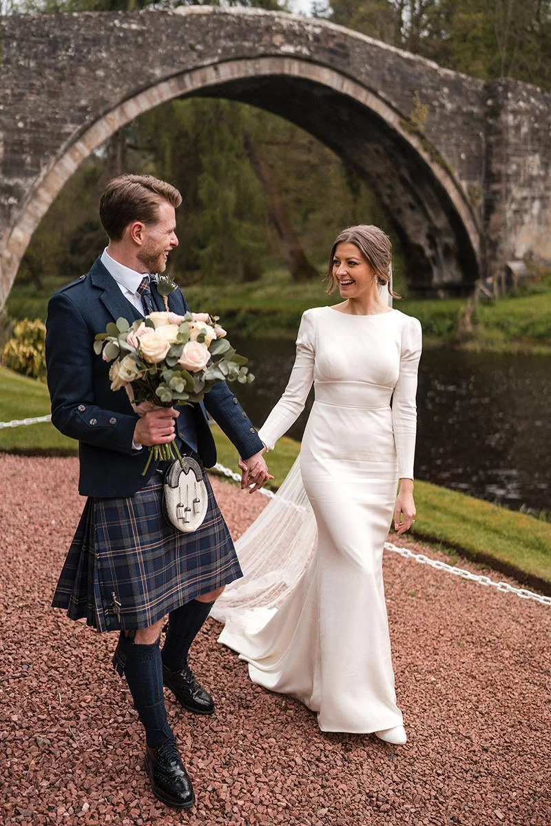 Bride and groom walking hand in hand at Brig o’ Doon in Ayrshire during a romantic wedding portrait session by Scotland wedding photographer Andy Hamilton.