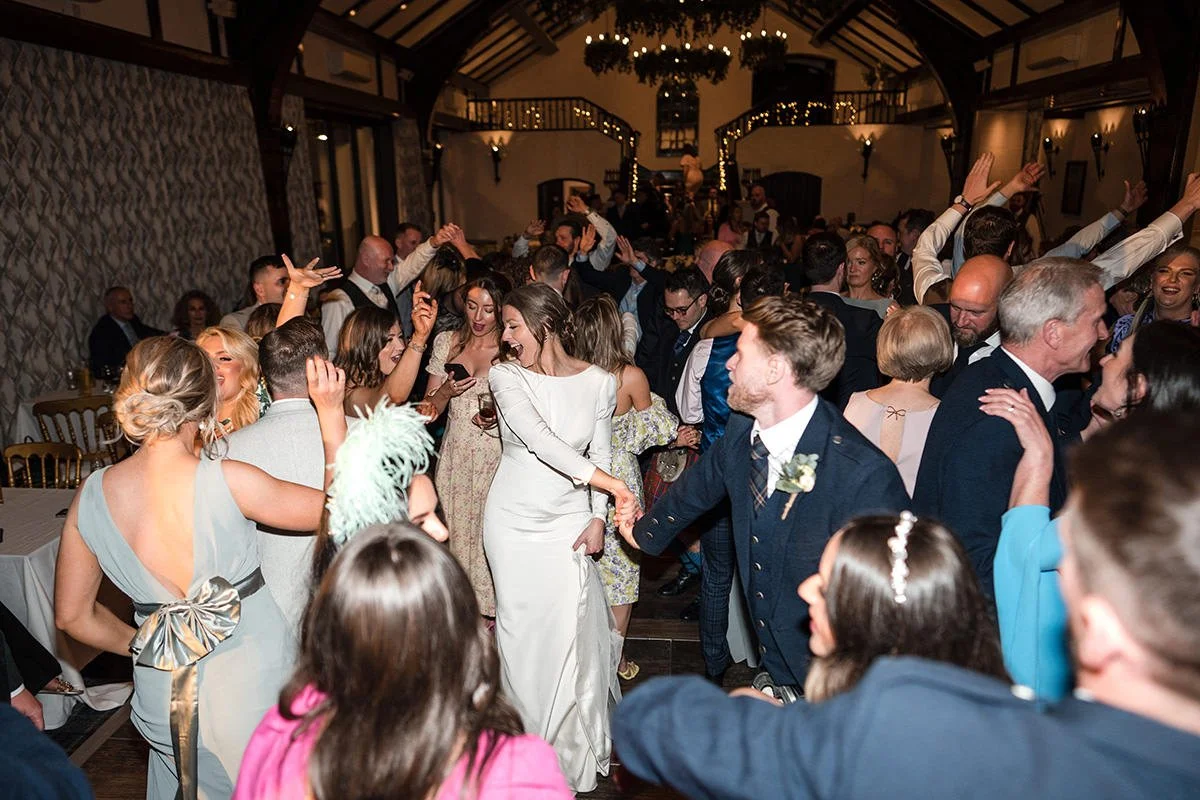 Wedding guests filling the dancefloor during an energetic evening reception at Brig o’ Doon House Hotel in Ayrshire, with the bride dancing among friends and family