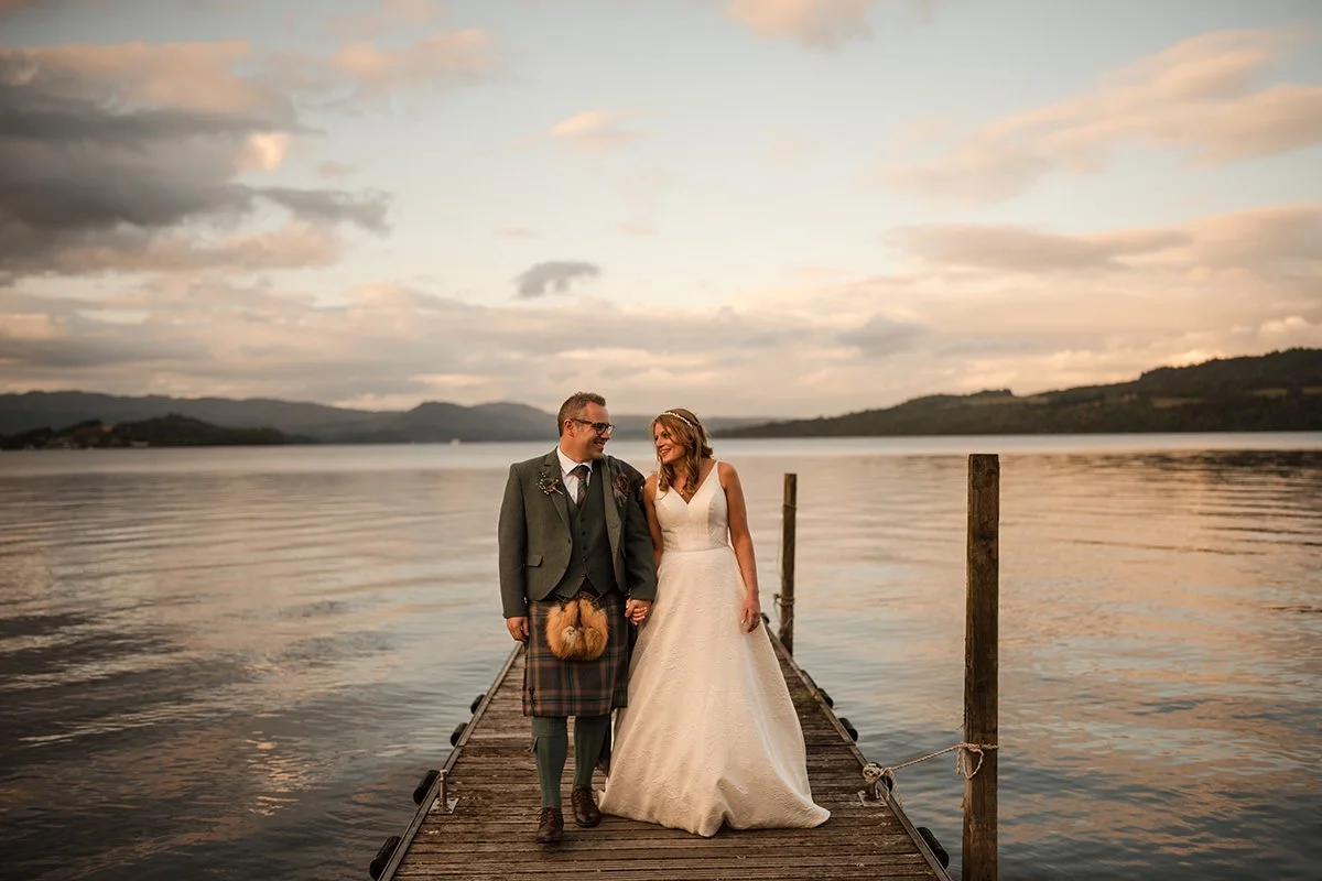 Bride and groom holding hands on the jetty at Cruin, Loch Lomond during sunset wedding portraits