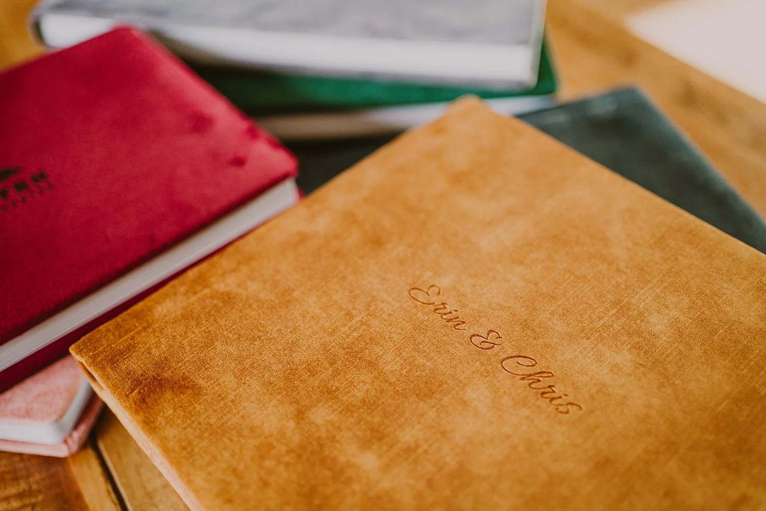 Stack of books, including a tan one with 'Eat & Drink' written on the cover, on a wooden table.