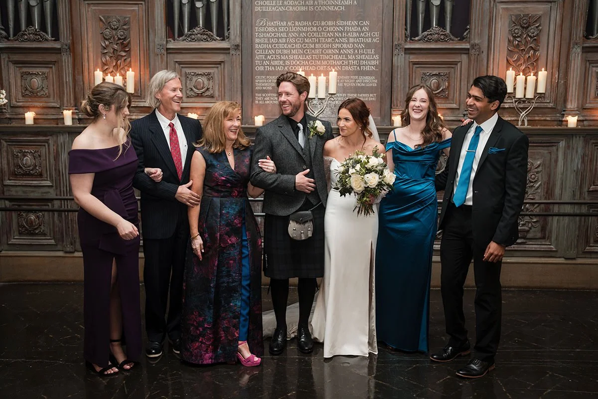 Bride and groom laughing with close family during relaxed wedding family photos inside an Edinburgh church, surrounded by candlelight