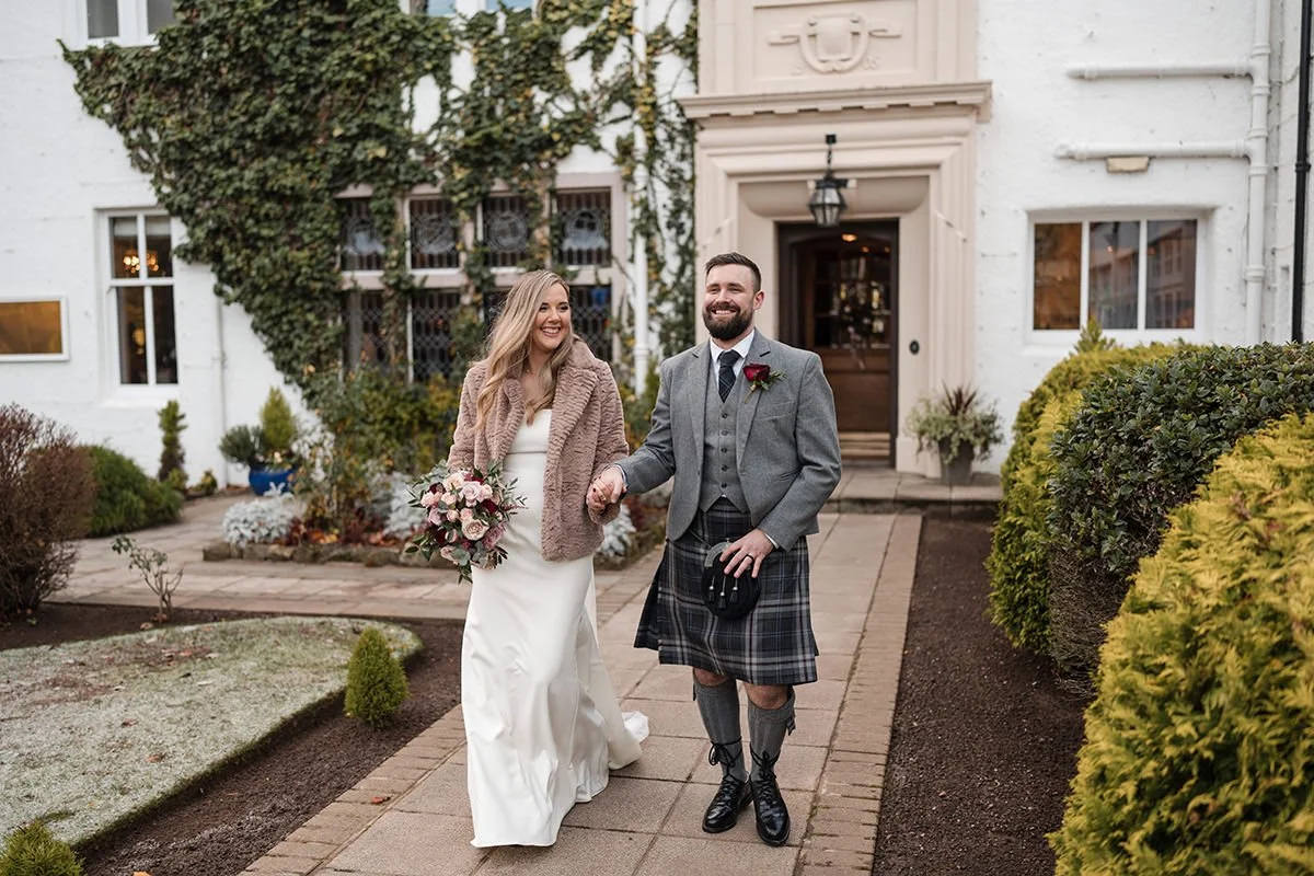 Bride and groom walking hand in hand outside Loch Green House Hotel after their wedding, relaxed and smiling