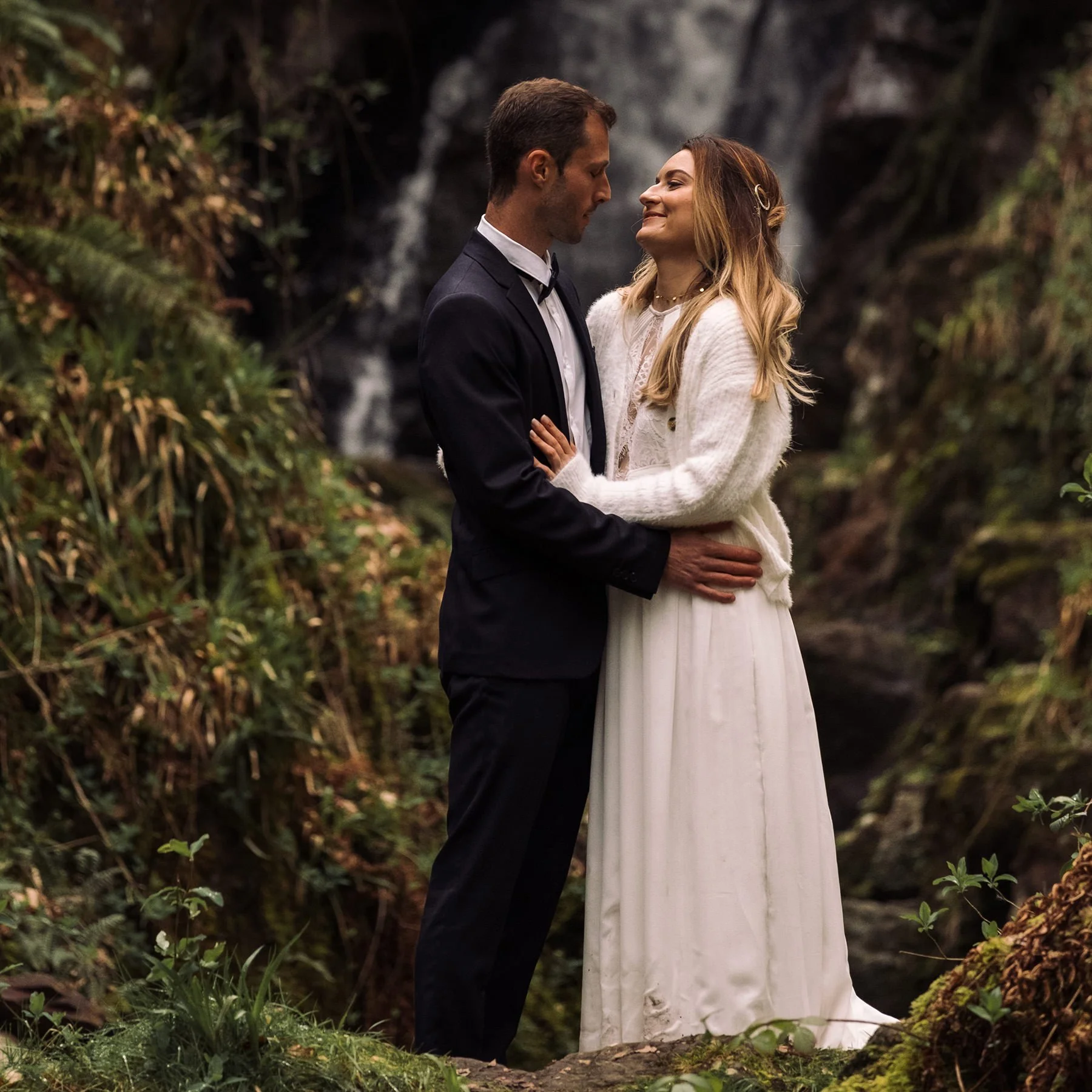 Couple sharing a quiet moment during a forest elopement beside a waterfall in Scotland