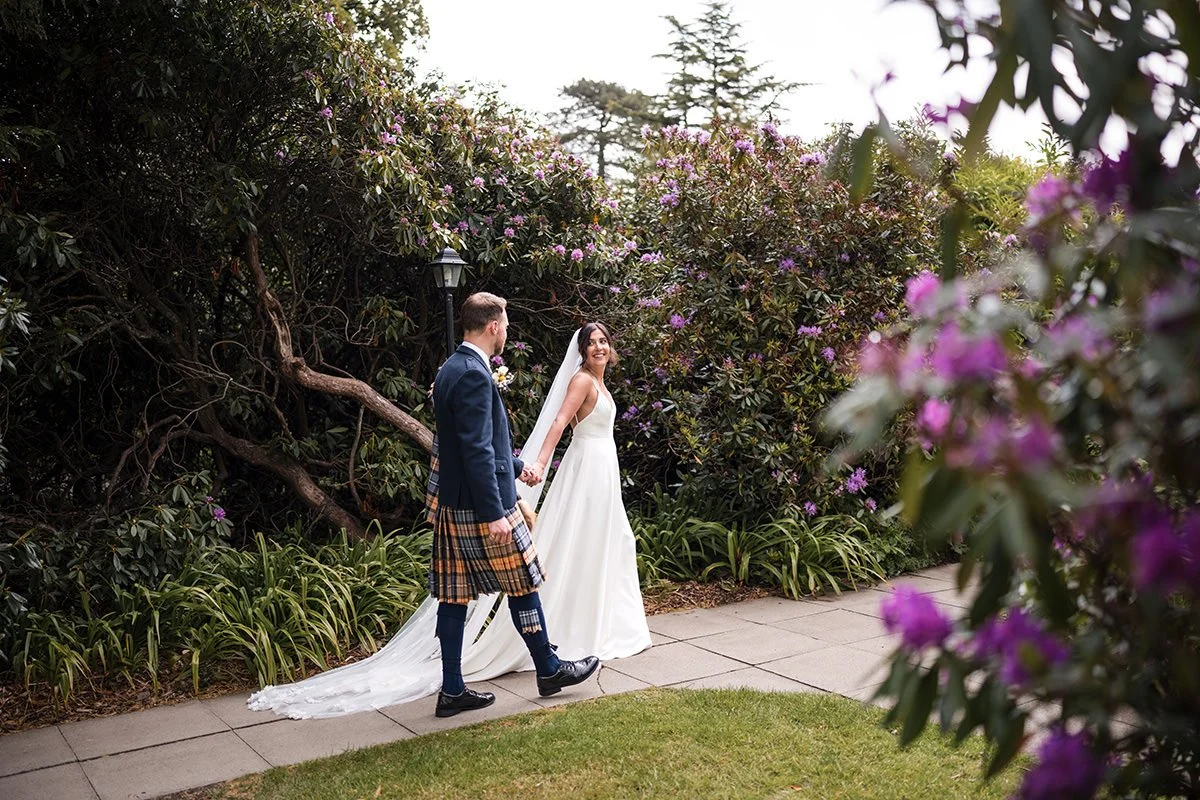 Bride and groom holding hands during relaxed wedding portraits in the gardens at Dundas Castle, Edinburgh