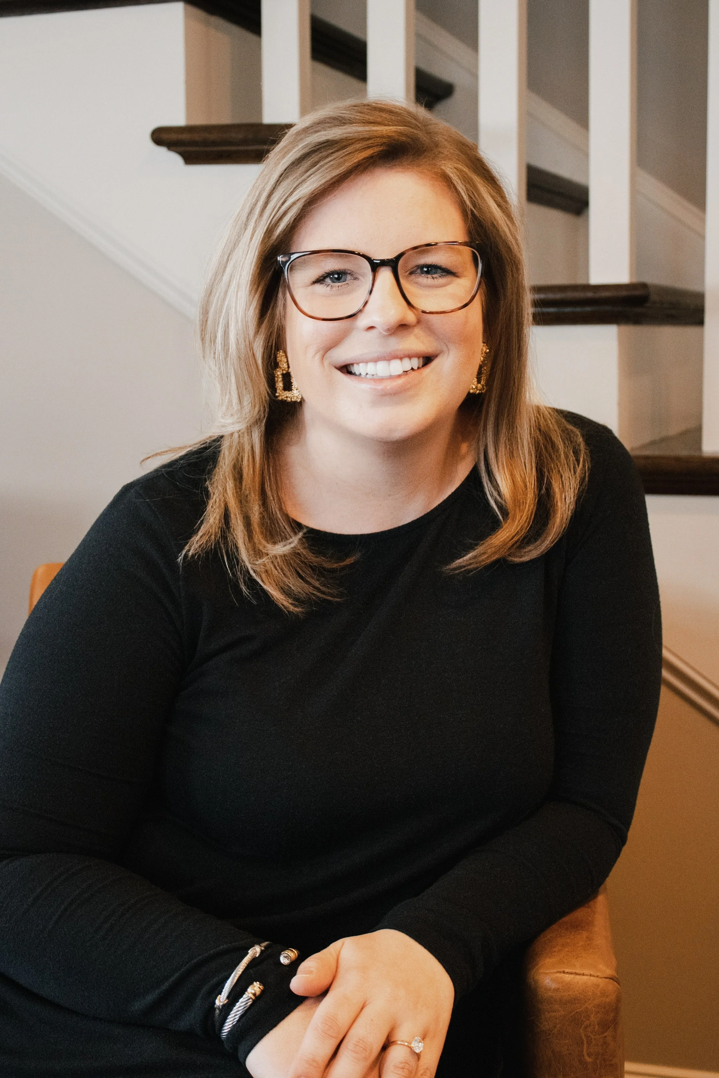 Allison Vega sitting in front of stairs, A headshot of Allison Vega, Murfreesboro & Middle TN Real Estate Expert
