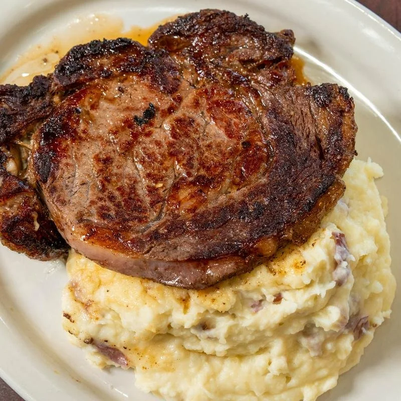 A plate of a cooked pork chop served with mashed potatoes.