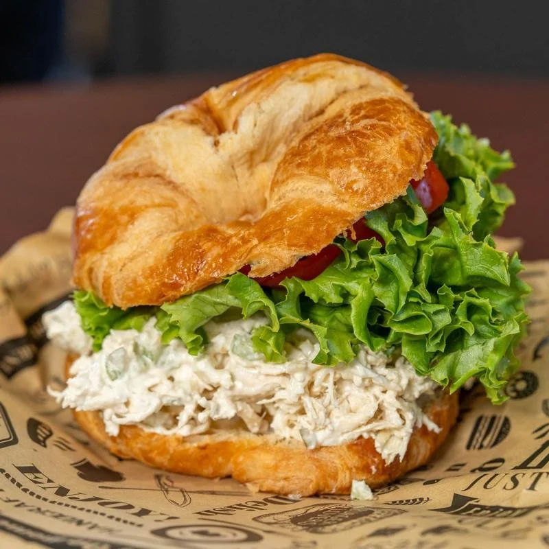 Chicken salad sandwich on a croissant with lettuce and tomato.