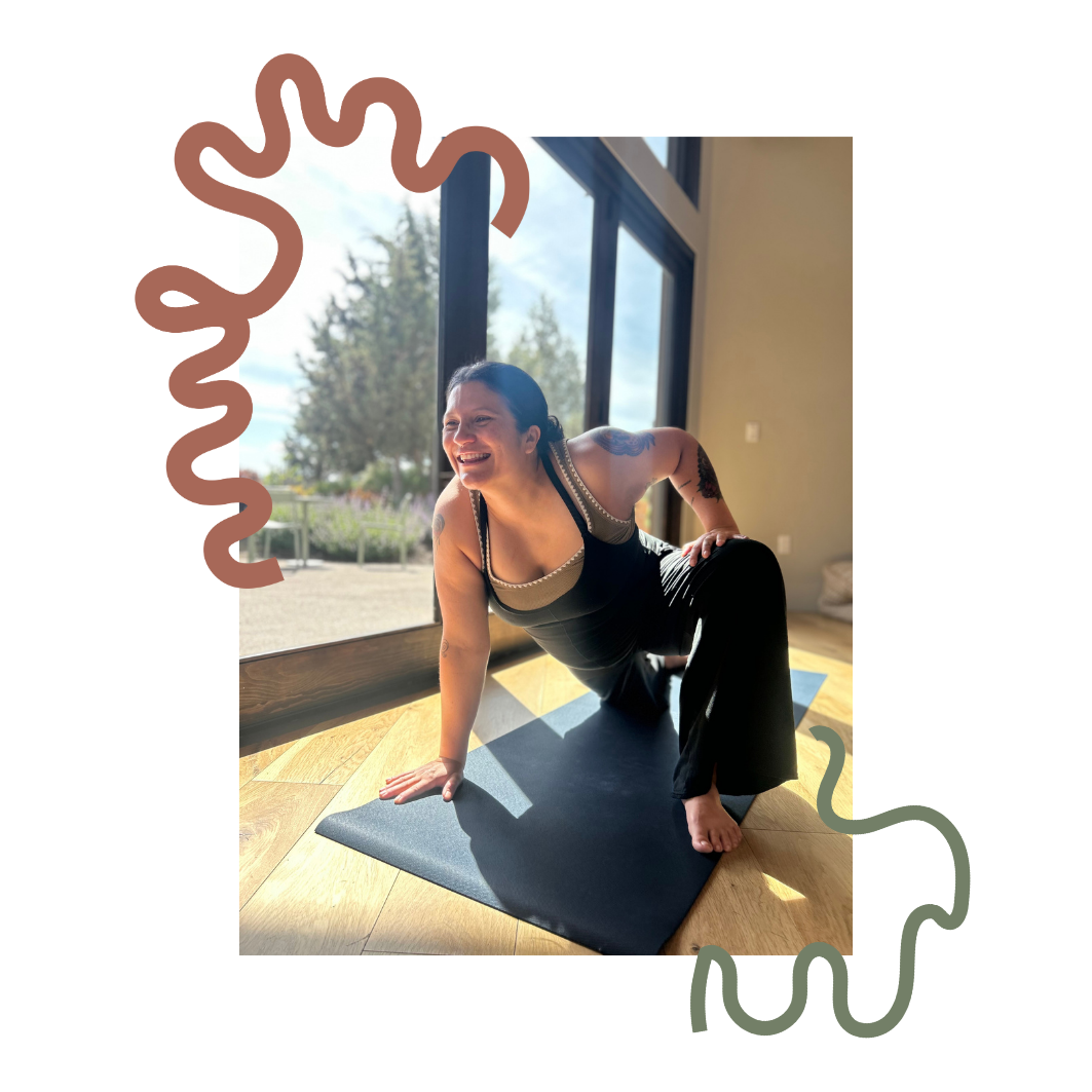 Woman practicing yoga on a black mat inside near large windows, smiling and looking outdoors on a sunny day. Baby and me yoga class, mommy and me yoga class