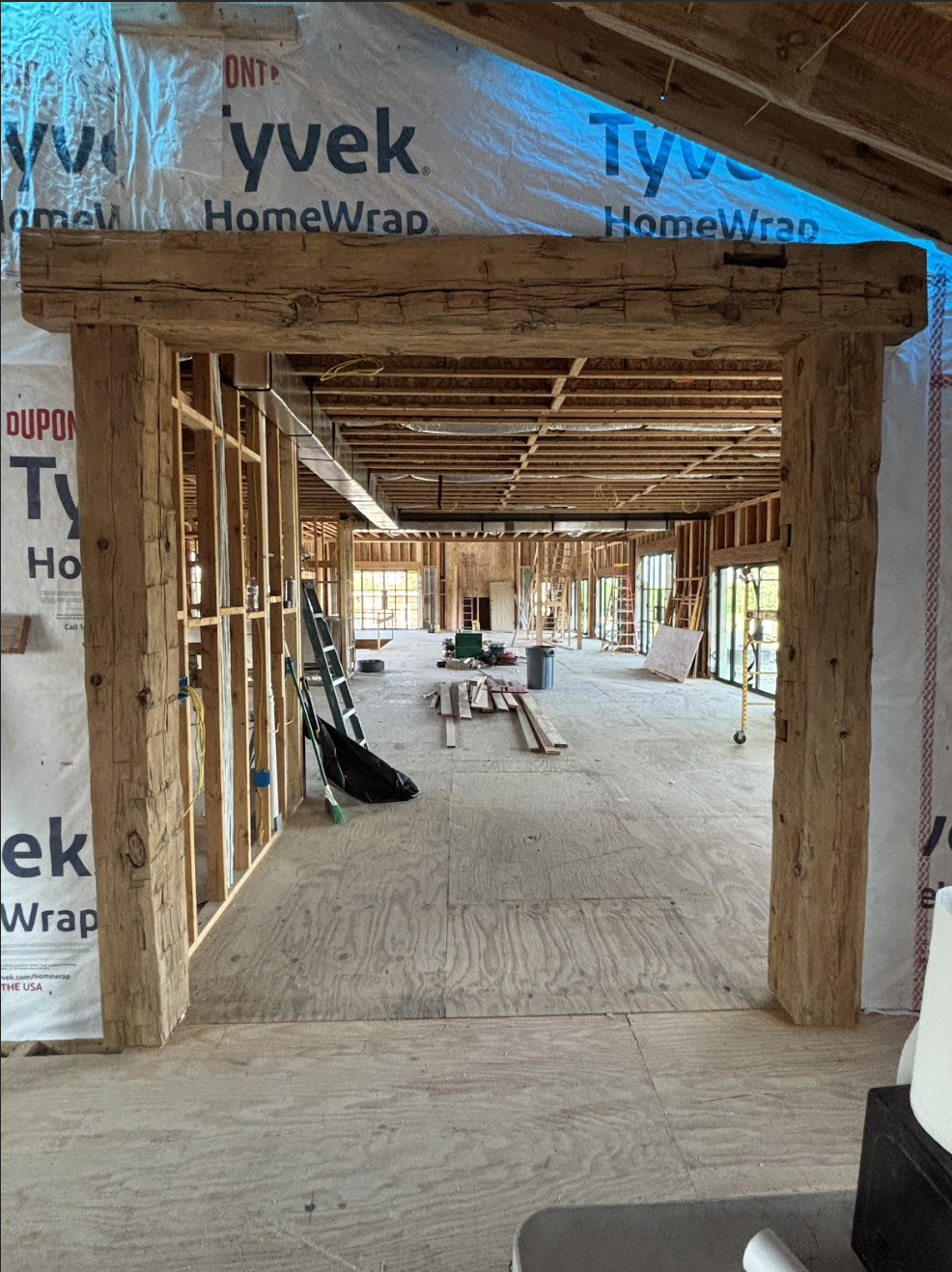 Wooden framing in a house under construction with open walls and ceiling, construction tools and materials on the floor.