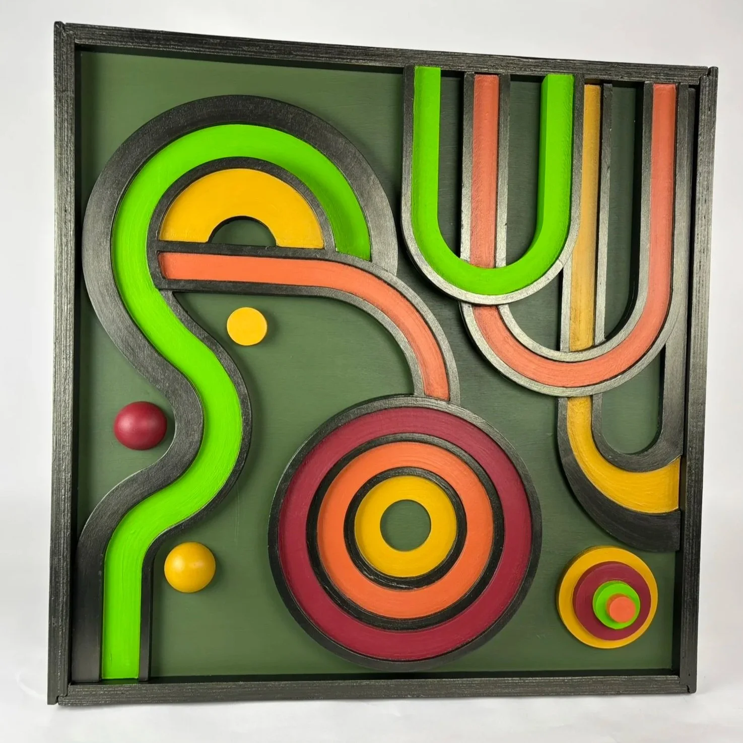 Colorful maze with curved pathways and three spherical balls, enclosed in a black wooden frame.