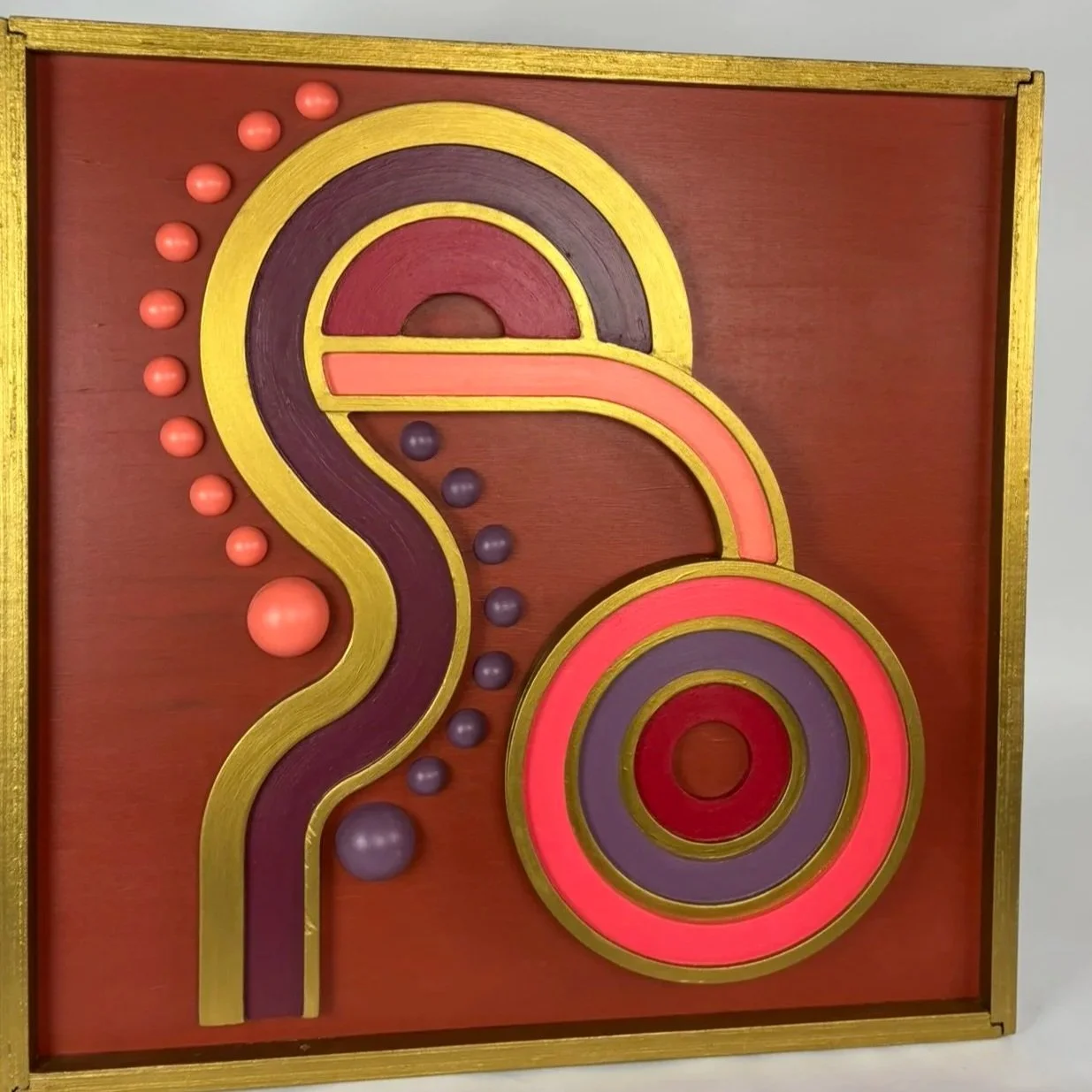 A vintage marble maze game with colorful pathways, circular and curved tracks, and small marbles on a wooden background.