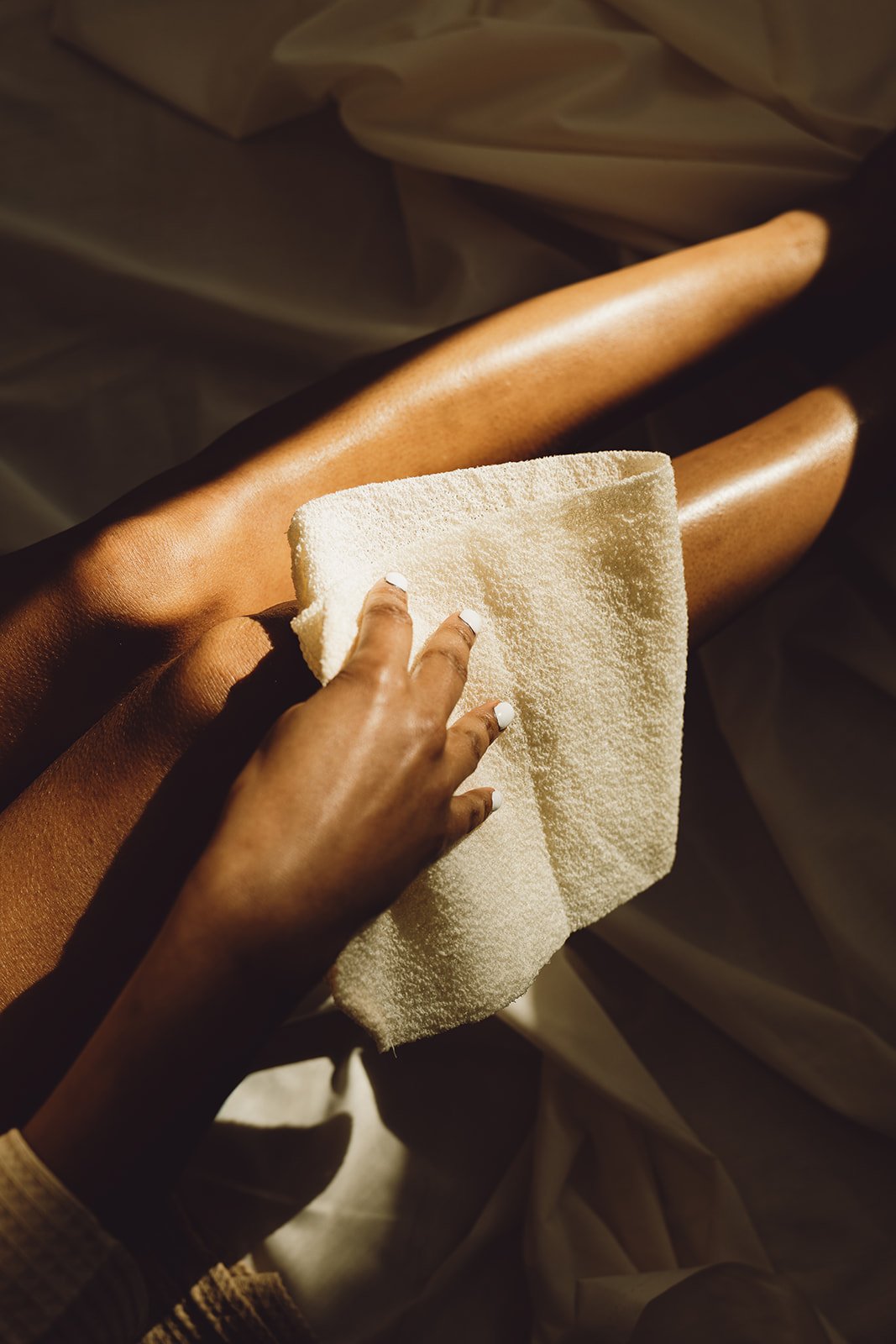 Person exfoliating their legs with a gentle exfoliating cloth.