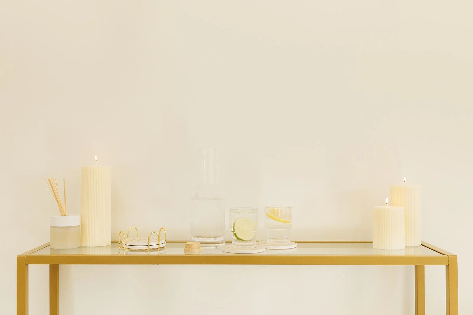 Decorative table with candles, glassware, and candles with lemon slices, minimalist style in neutral tones.