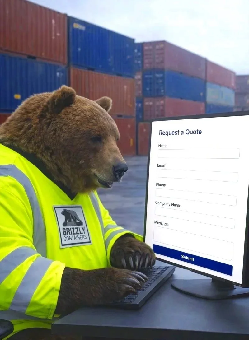 A Grizzly bear wearing a yellow safety vest with a 'Grizzly Containers' logo sitting in front of a computer at a shipping yard with stacked shipping containers in the background. Grizz is filling out a request a quote form.