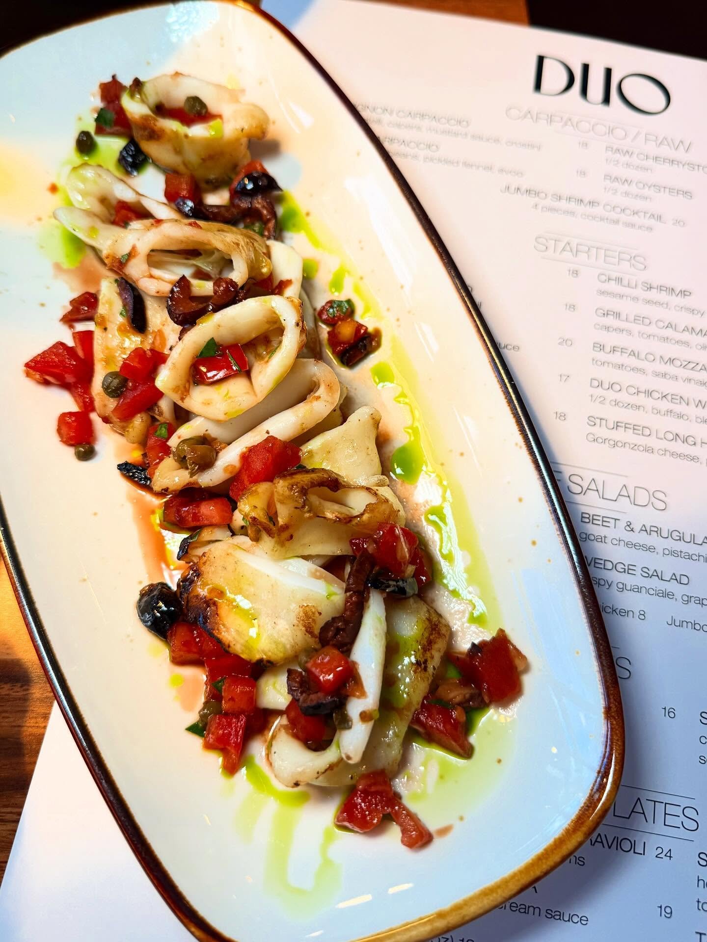 Grilled calamari with capers, tomatoes, and olives in a refreshing vinaigrette!🦐✨