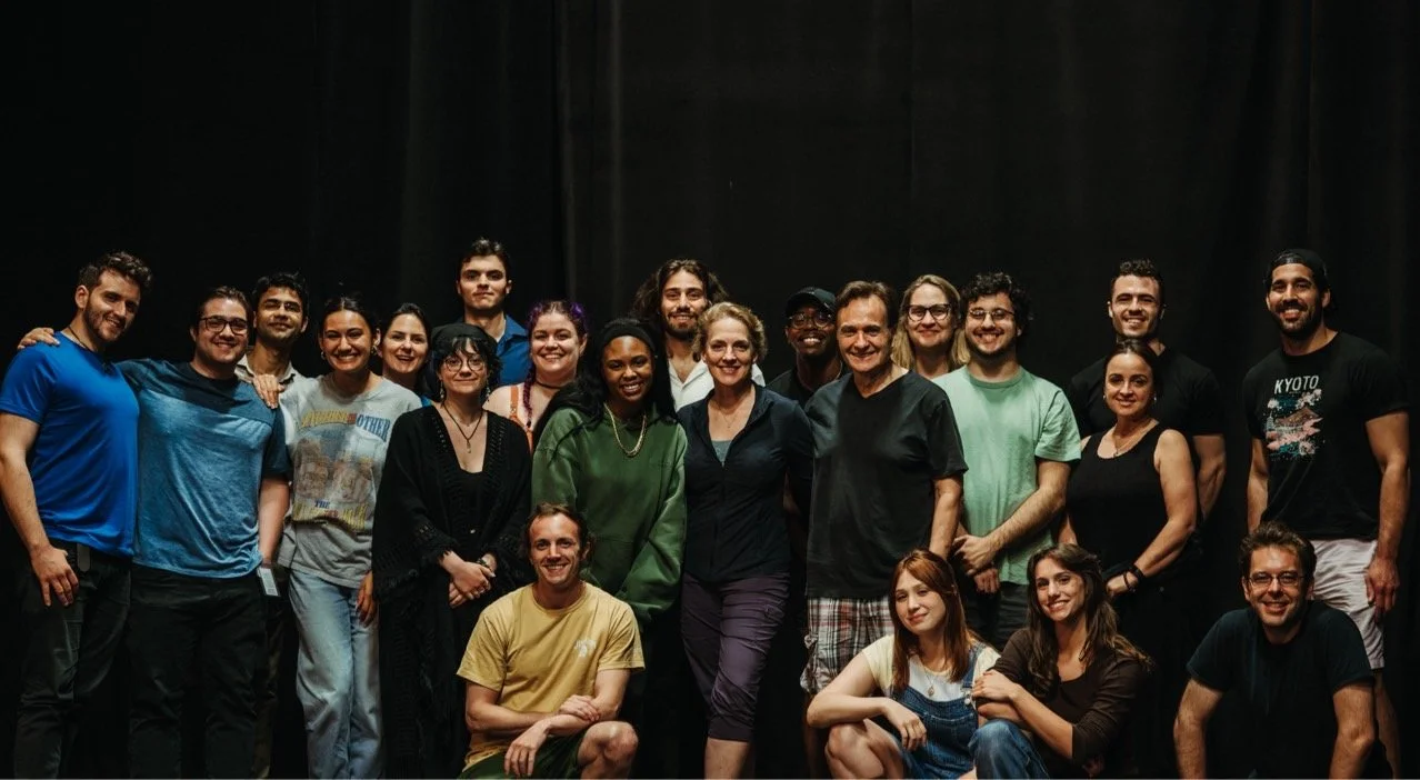 Group of diverse people posing for a photo on a dark stage, smiling.