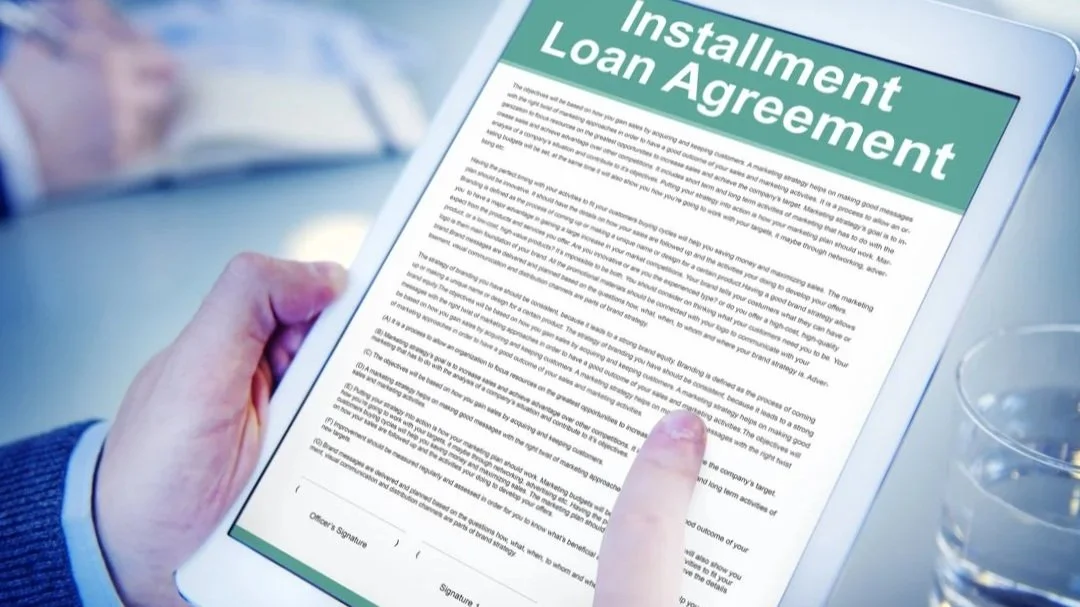 A person holding a tablet displaying an 'Installation Loan Agreement' document.