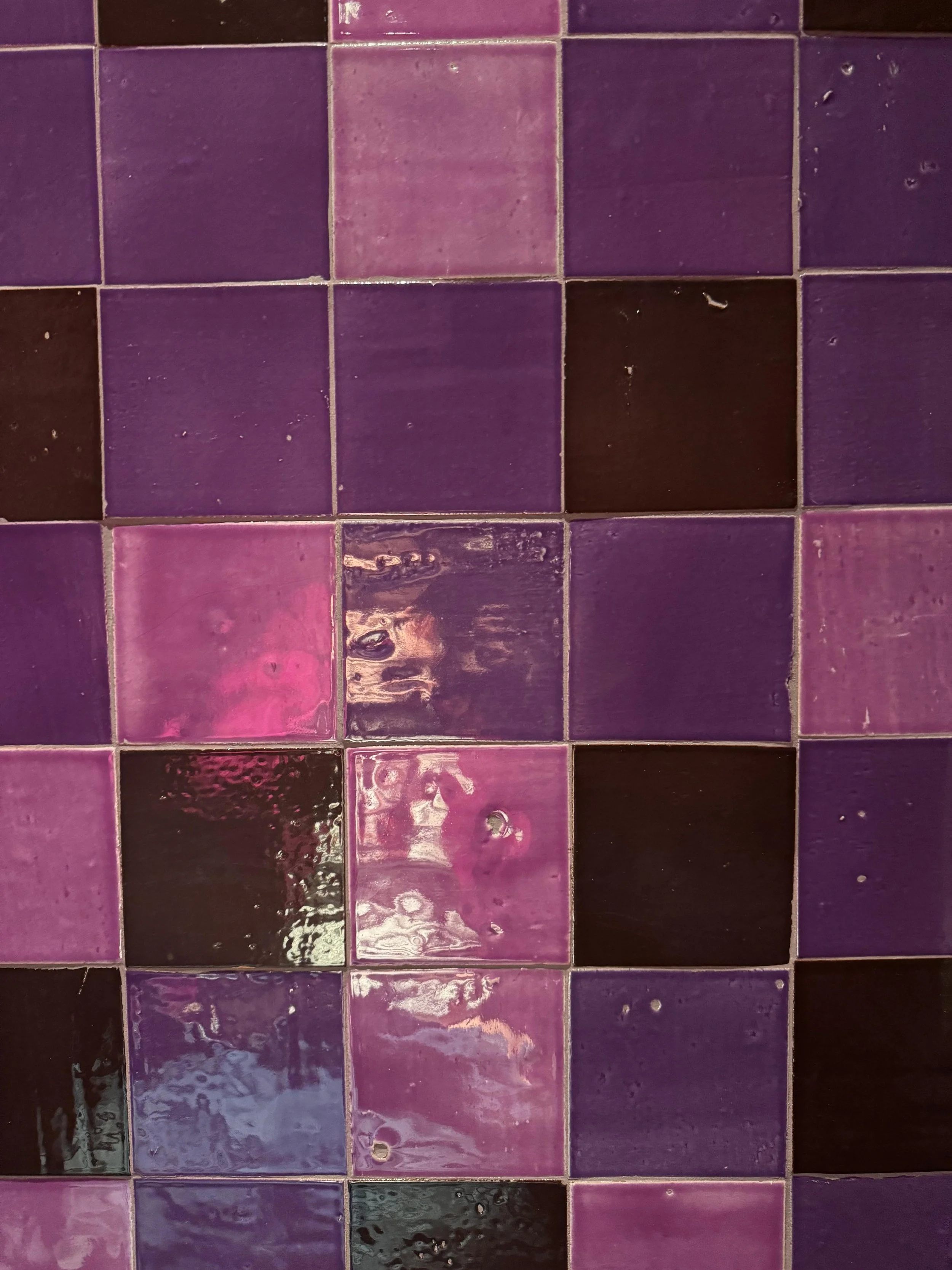 Close-up of purple and black ceramic tiles on a wall.