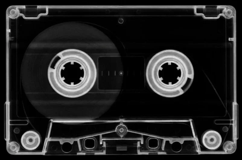 A transparent audio cassette tape showing the internal spools and tape.