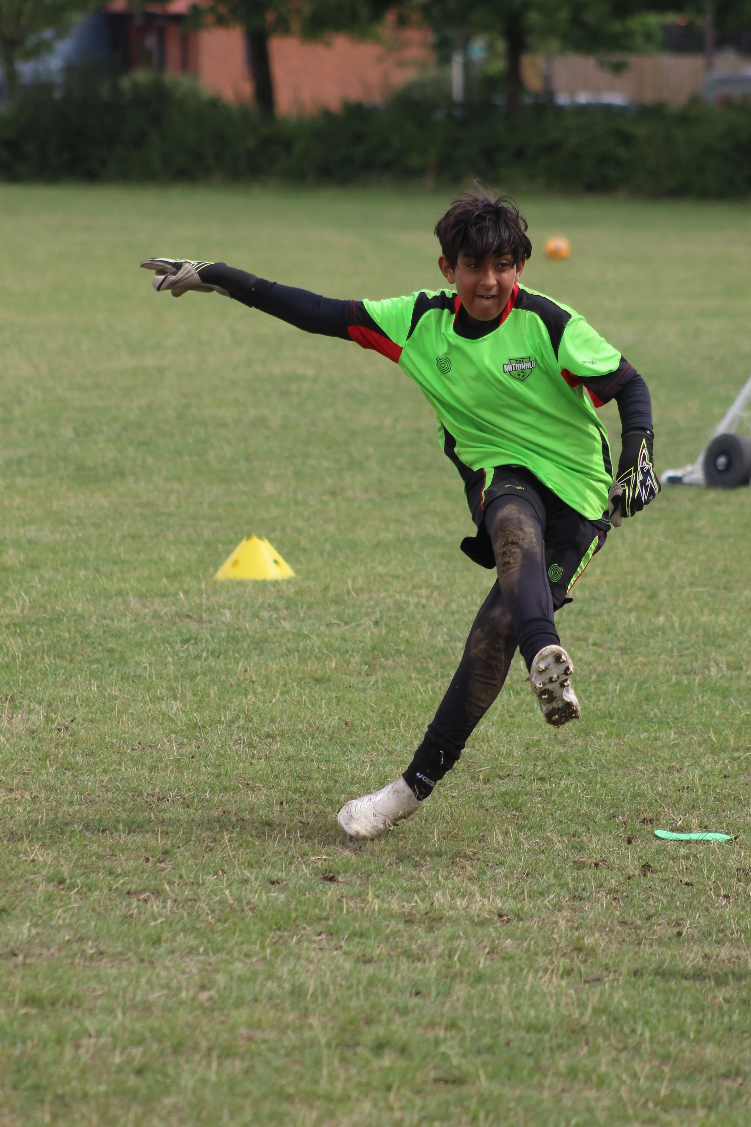 A  goalie in green jersey mid kick.