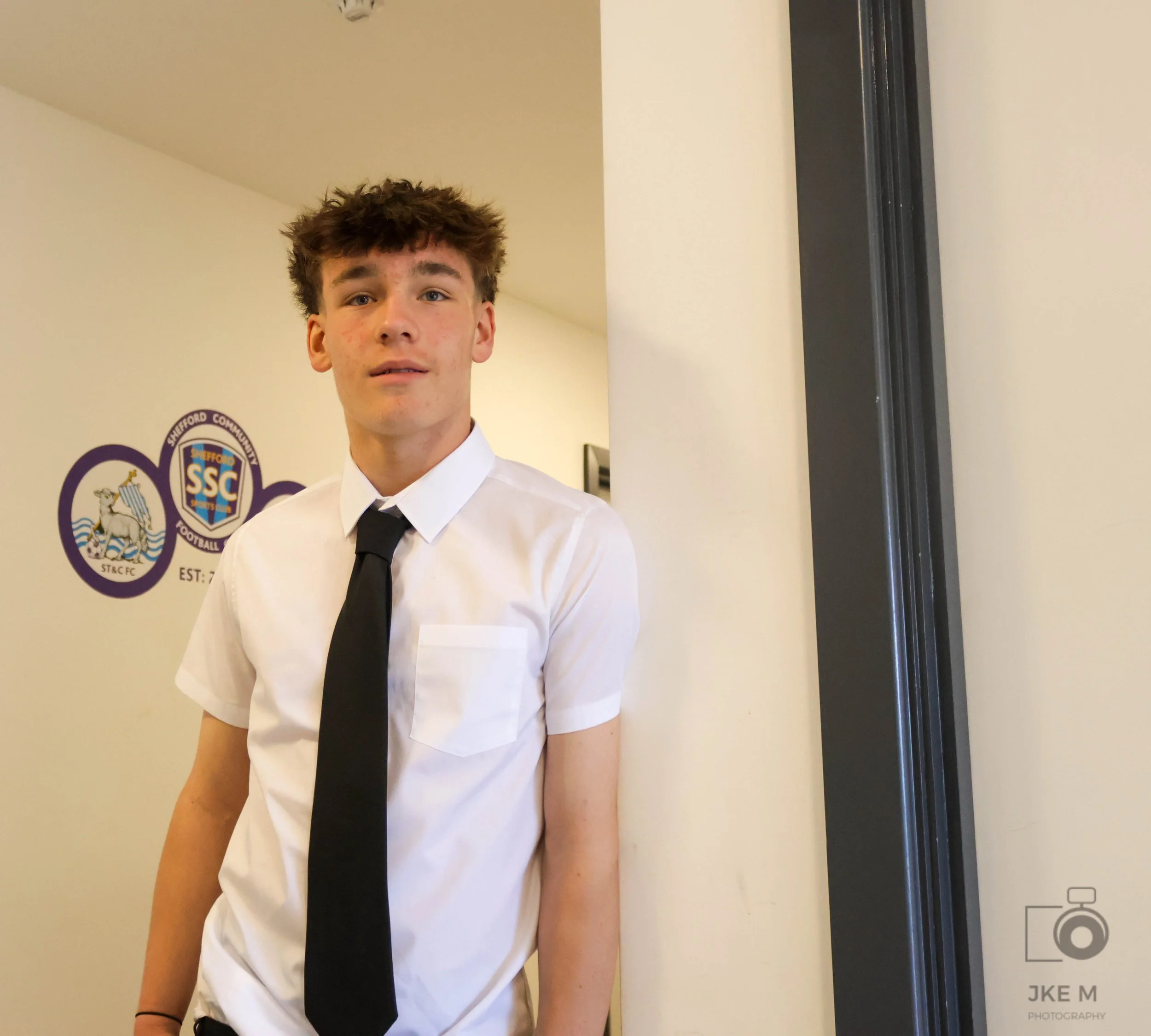 Young man with wearing a white shirt and black tie standing indoors