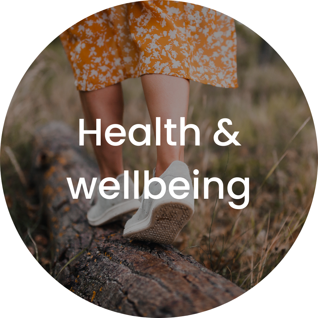 Person walking on a log in a natural outdoor setting, wearing a floral dress and white sneakers, with the text 'Health & wellbeing' overlaid.