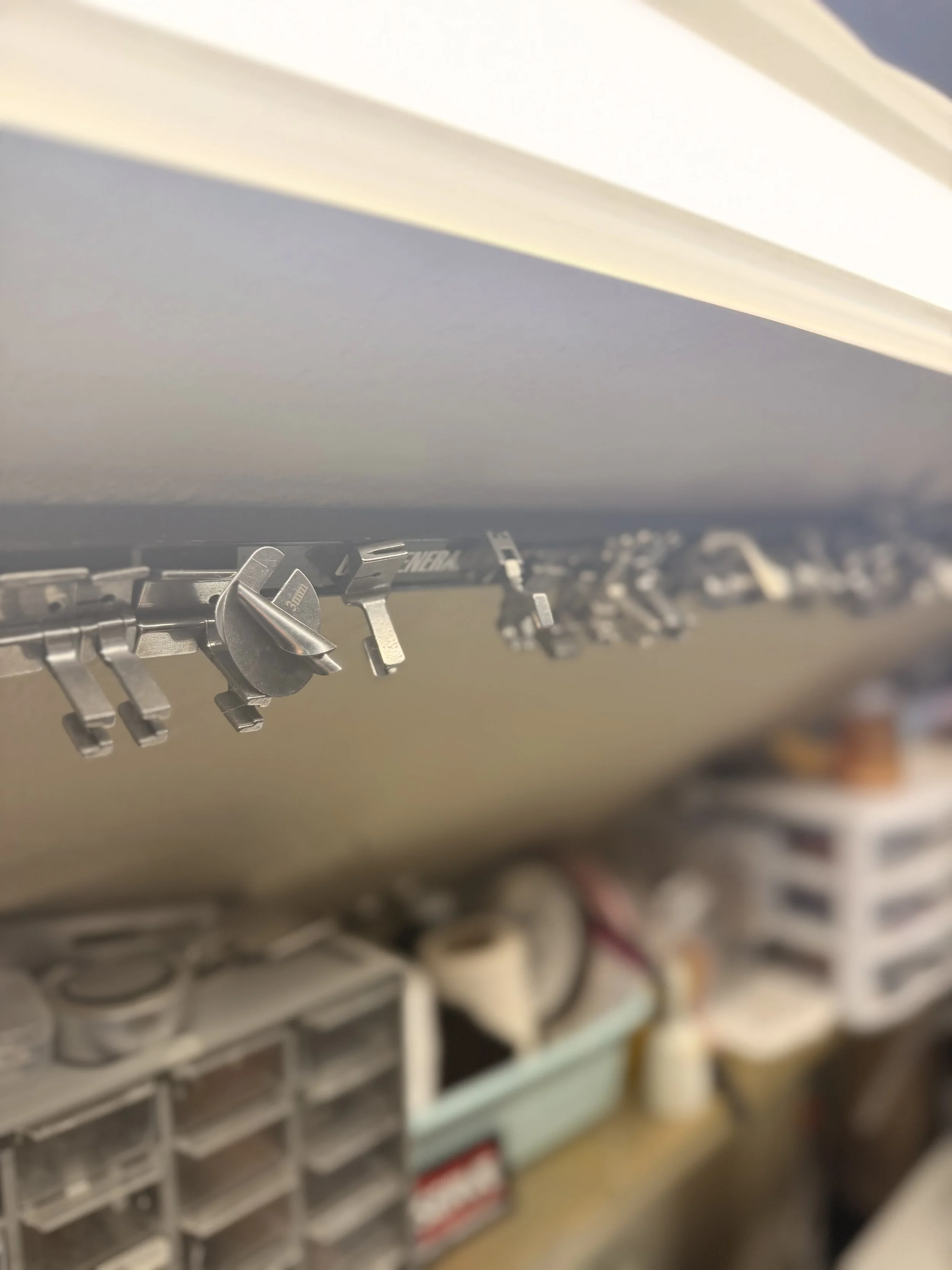 A blurry image of a hardware store shelf with bins and hooks, possibly containing screws or other small items.