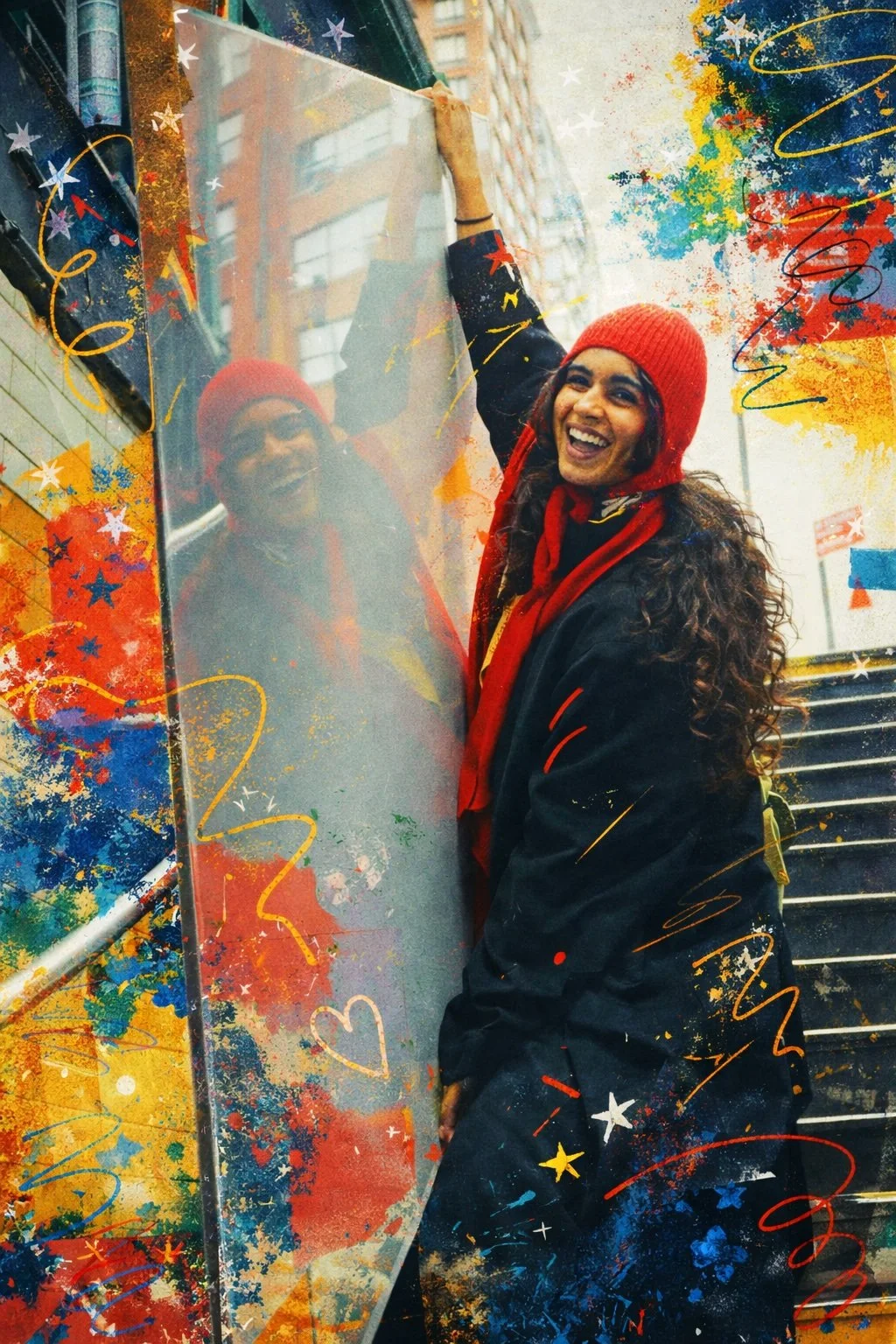 A smiling woman in a red beanie and black jacket with red accents, standing outdoors next to a reflective glass surface, with staircases and buildings in the background. The photo has festive colorful confetti, heart, and star graphics overlaid.