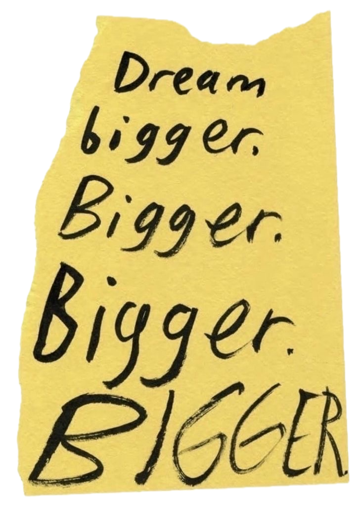 Yellow torn paper with handwritten motivational message: 'Dream bigger. Bigger. Bigger. Bigger. BIGGER'.
