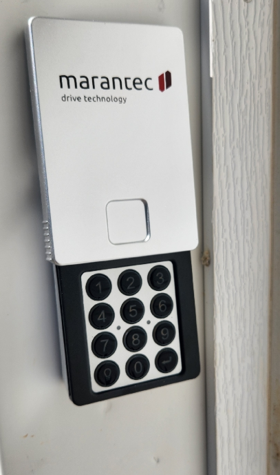 Install garage door keypad remote control with a keypad and a small display, mounted on a wall panel.