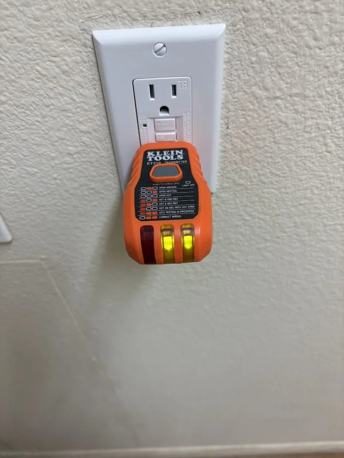 Electric outlet with a Klein Tools circuit tester hanging from the outlet. GFCI installation, electrician near me