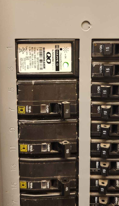 Close-up of an electrical circuit breaker panel with black switches and labels, including a Siemens circuit breaker at the top. Breaker installation, electrician near me