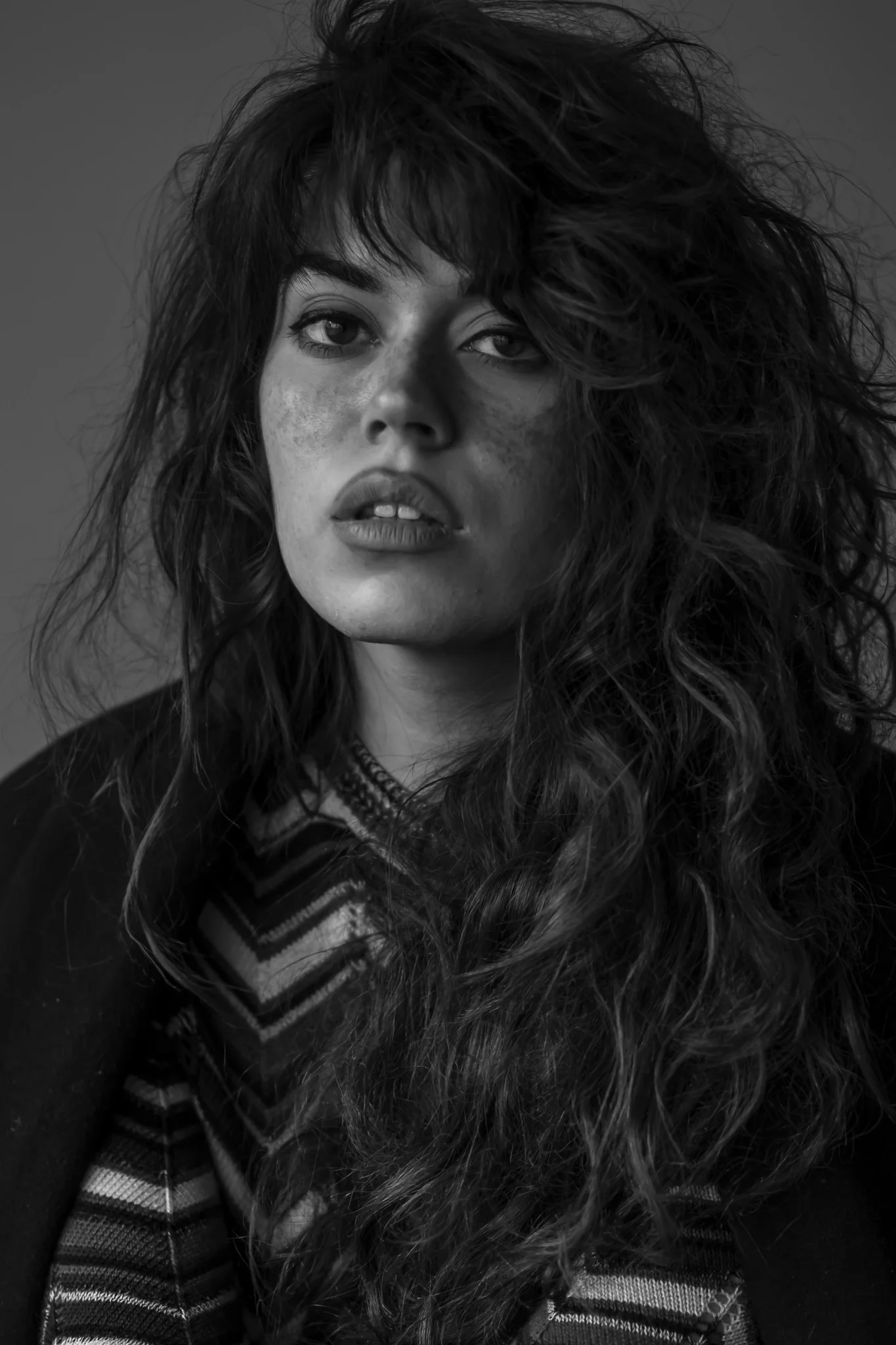 Portrait noir et blanc d'une femme avec de longs cheveux bouclés, regardant vers l'avant.