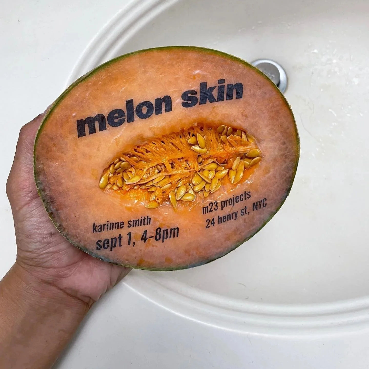 Half of a cantaloupe with a label that reads 'melon skin' and contains event details including a name, date, time, and location, with the inside of the melon showing seeds and orange flesh.