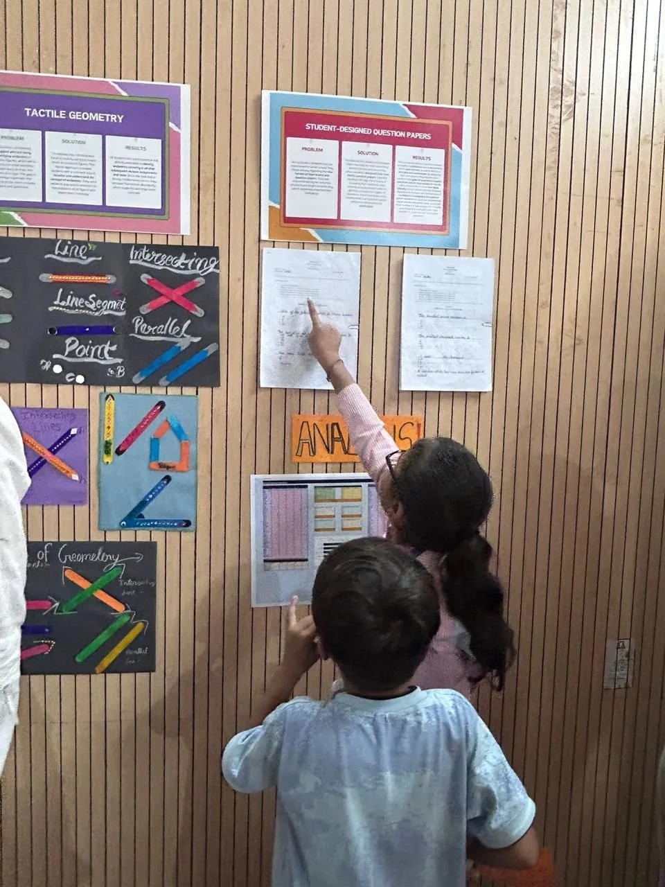 A student showing her paper on display to her younger brother :')