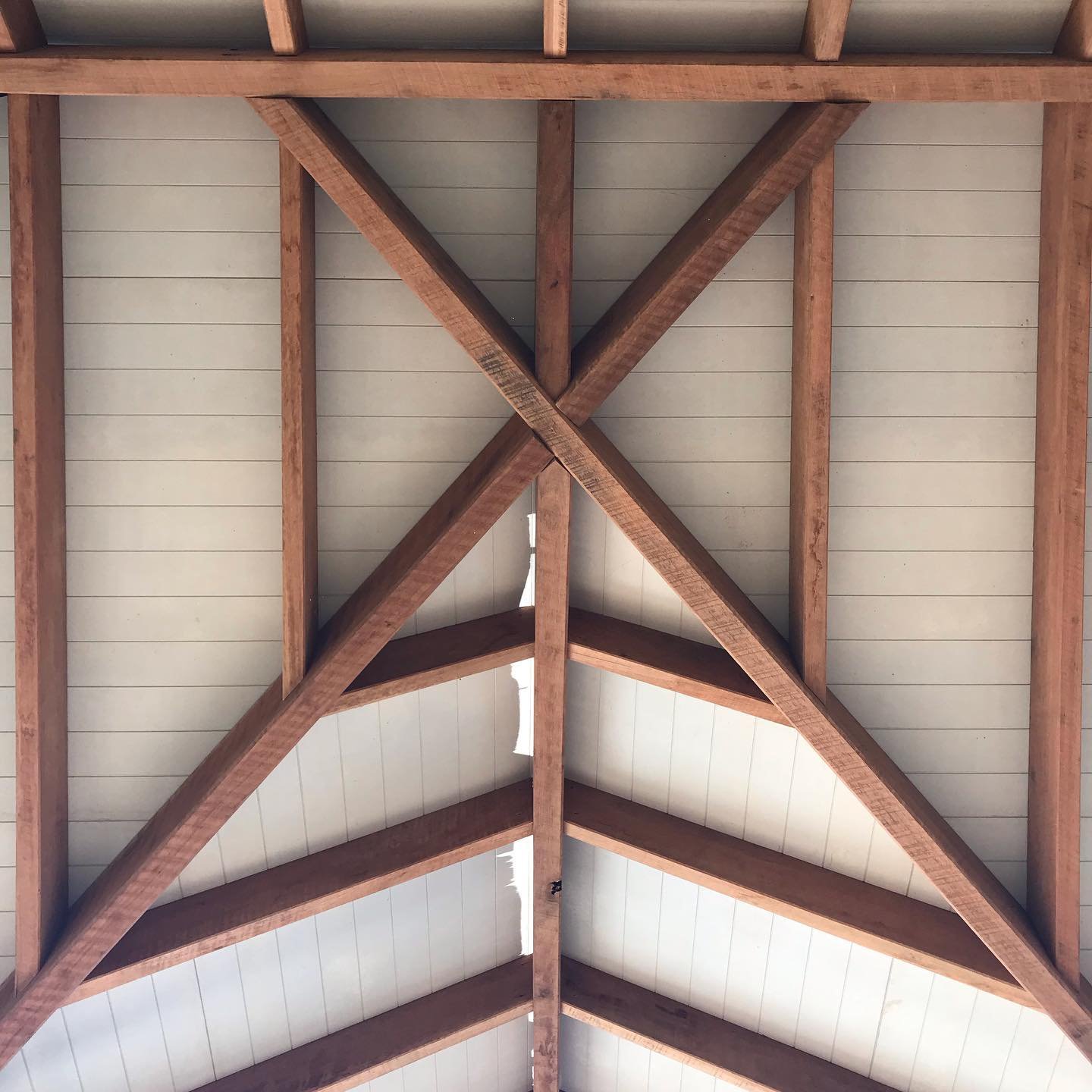 The ceiling of a building with exposed wooden beams forming a decorative pattern.