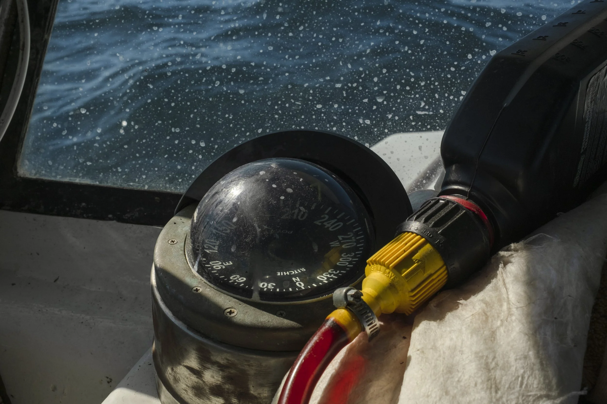 A compass and a navigation device on a boat, with water visible outside the boat's windshield.