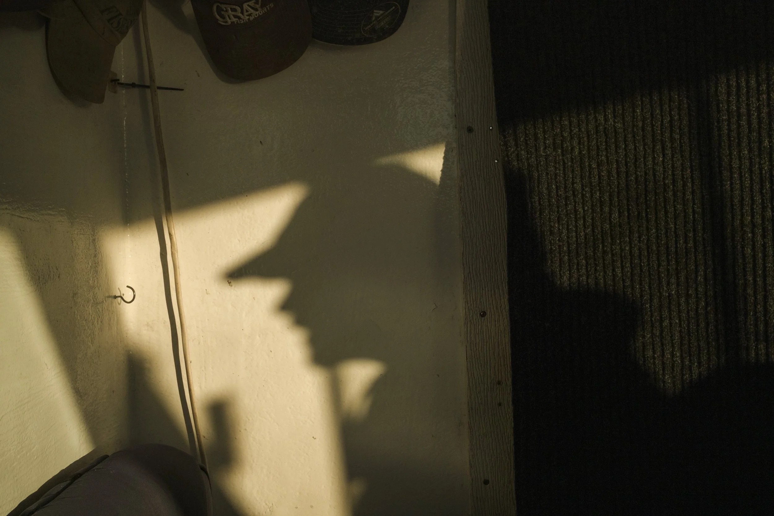 Shadow of a person with a hat on a wall, with sunlight creating the shadow.