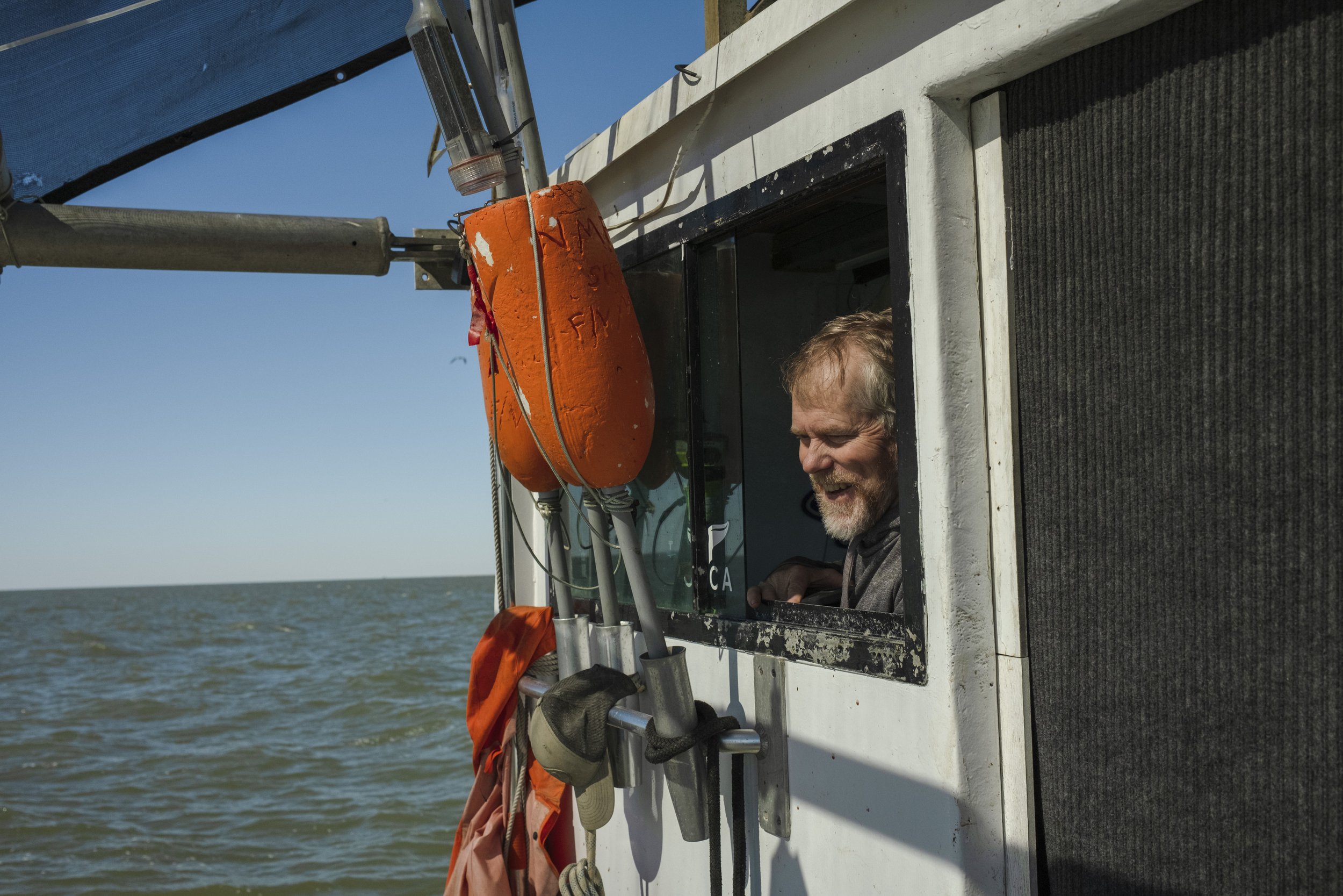 Man smiling from boat window on a body of water