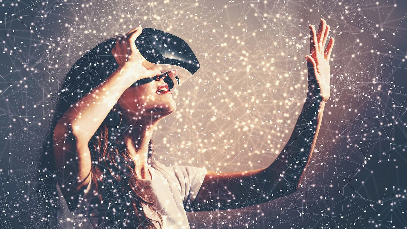 A woman wearing a virtual reality headset is reaching out with one hand and looking upwards. Digital light effects and network-like lines surround her, creating a futuristic, tech-inspired scene.