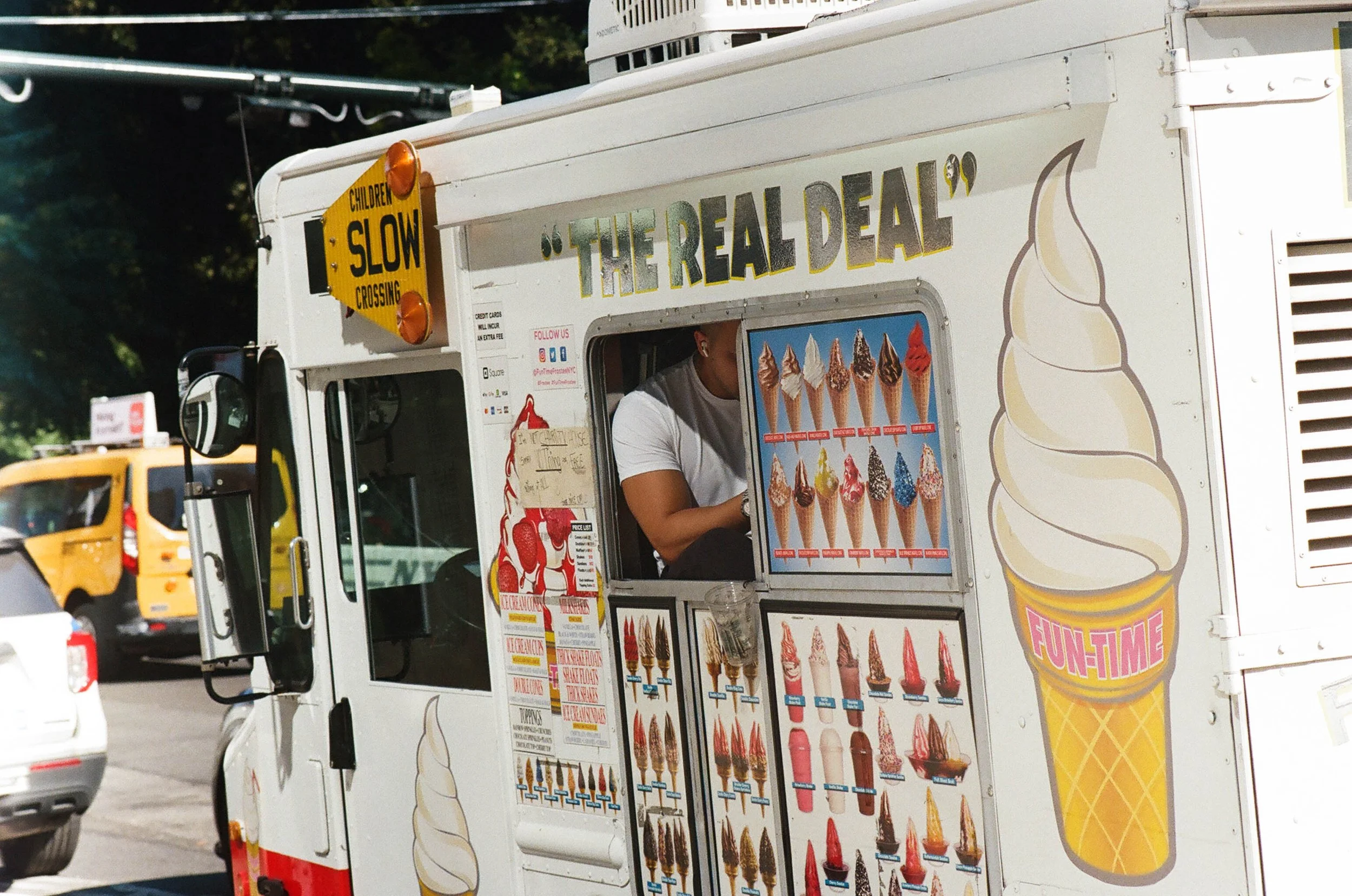 Ice cream truck with a menu of various ice cream cones and treats, featuring colorful images and a large ice cream cone illustration on the side.