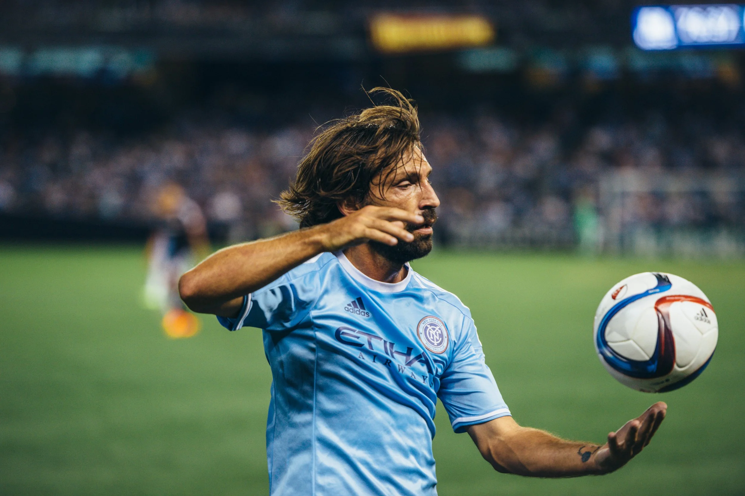 Soccer player in Manchester City jersey catching a soccer ball during a match.