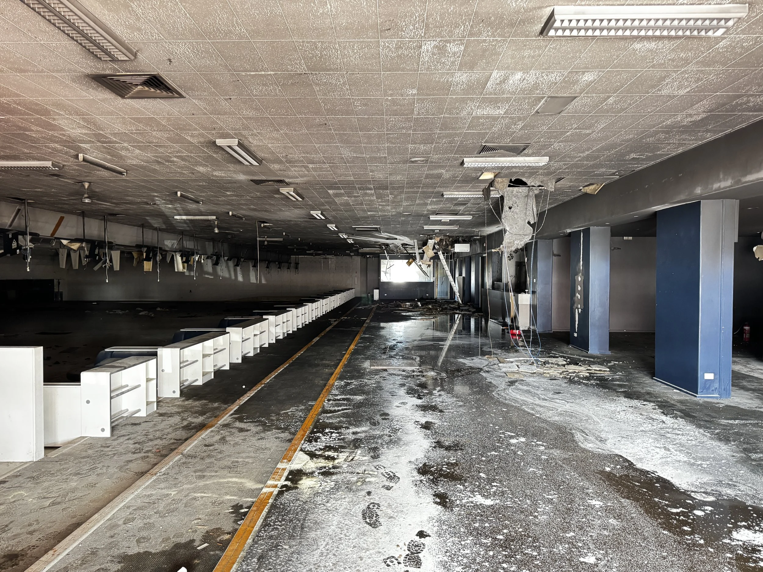 Damaged and burned interior of a building, debris on the floor, some walls and ceiling damaged.