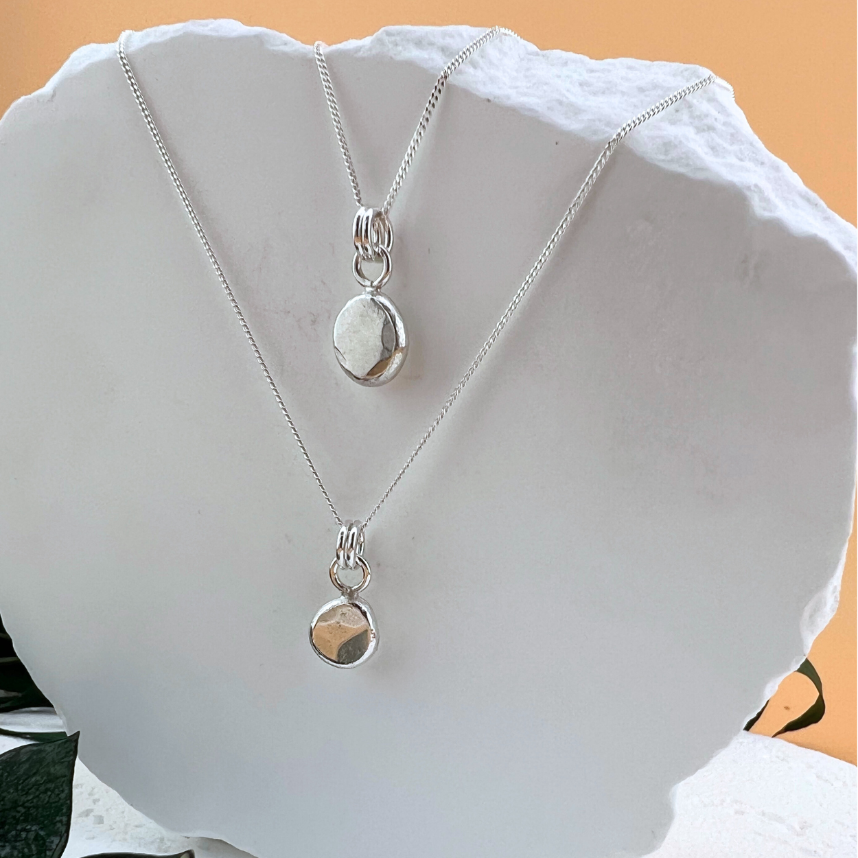 Side angle view of the Hope Stone Necklace showing the subtle depth, organic shape, and hand-hammered texture of the sterling silver pebble pendant.