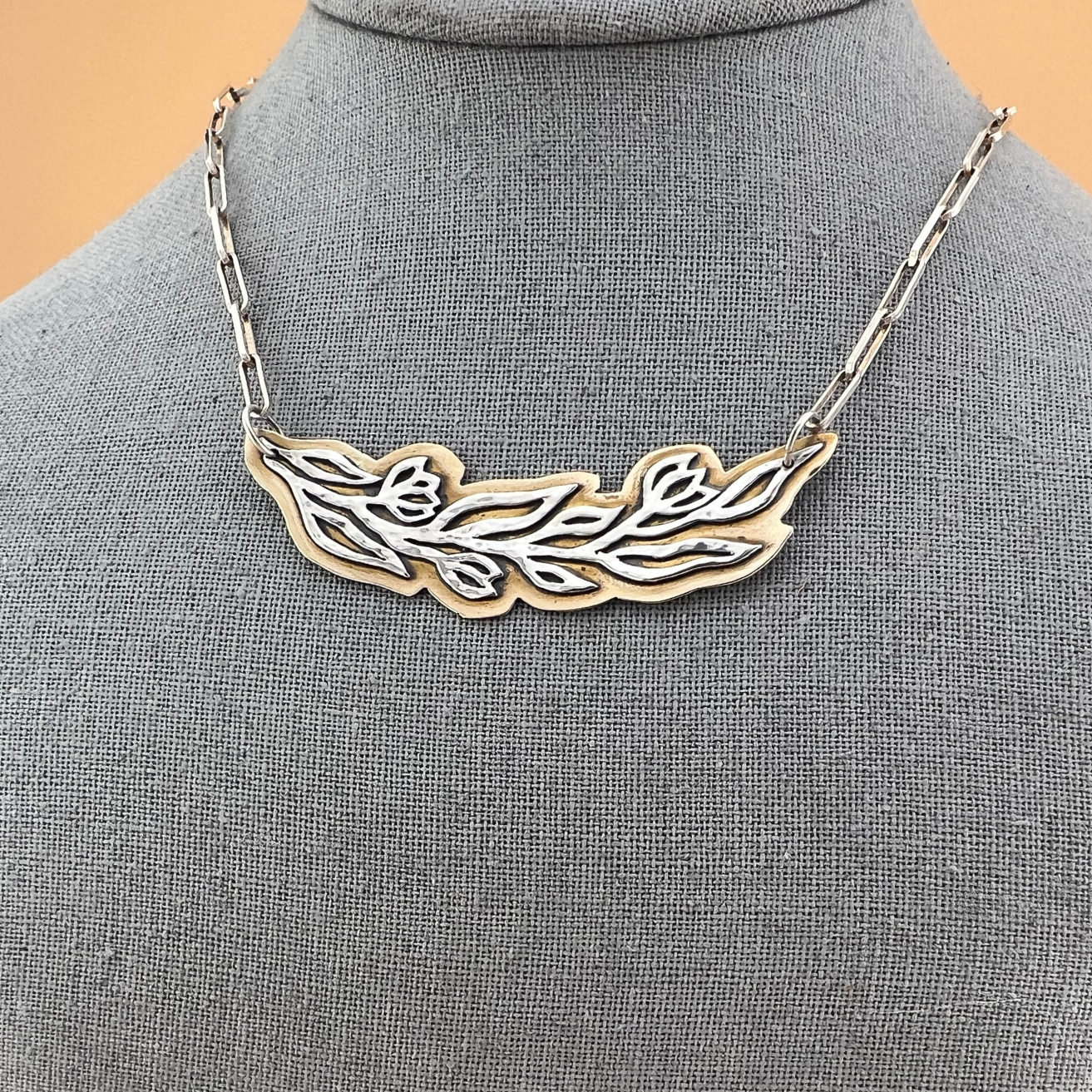 Bold mixed-metal vine statement necklace in sterling silver and brass, close up to see the details.