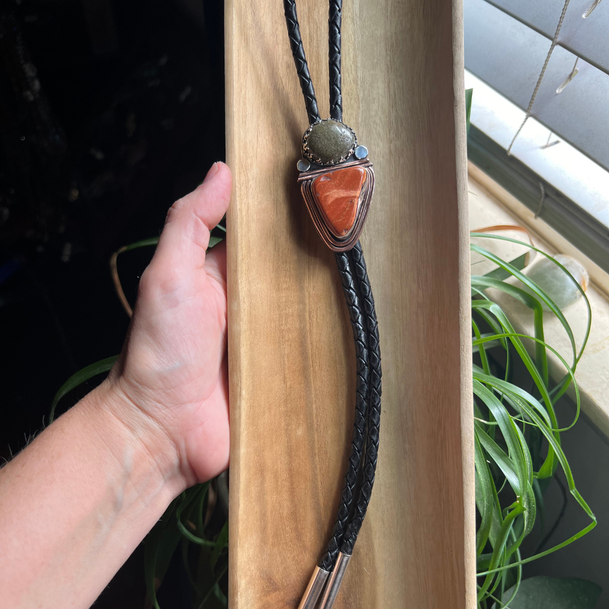 Custome bolo tie with red and green agate stones on black braided leather.