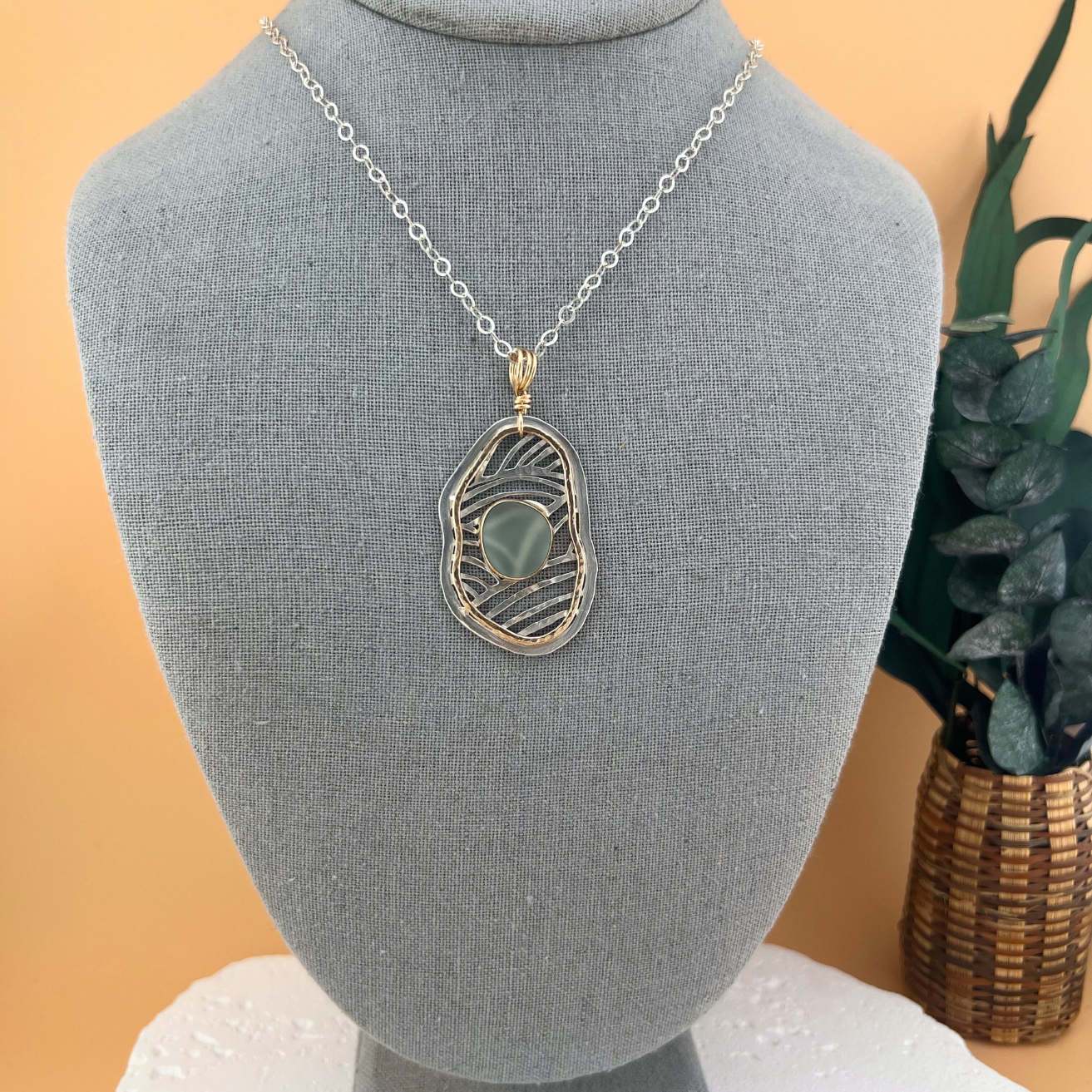 Mixed metal sea glass pendant necklace with flowing openwork design.
